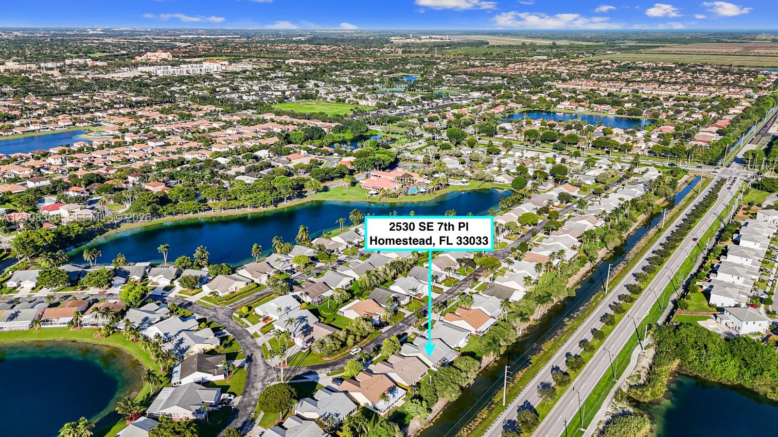 Aerial perspective of a residential property situated in a planned community featuring multi-acre lakes and dense perimeter landscaping