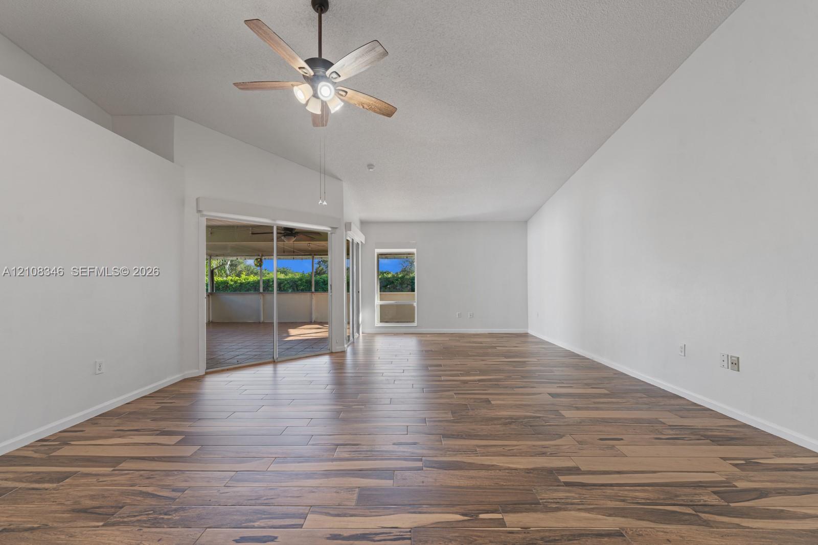 Vaulted ceilings featuring a five-blade ceiling fan with integrated lighting, wood-finish flooring, and sliding glass doors Vaulted ceilings featuring a five-blade ceiling fan with integrated lighting, wood-finish flooring, and sliding glass doors