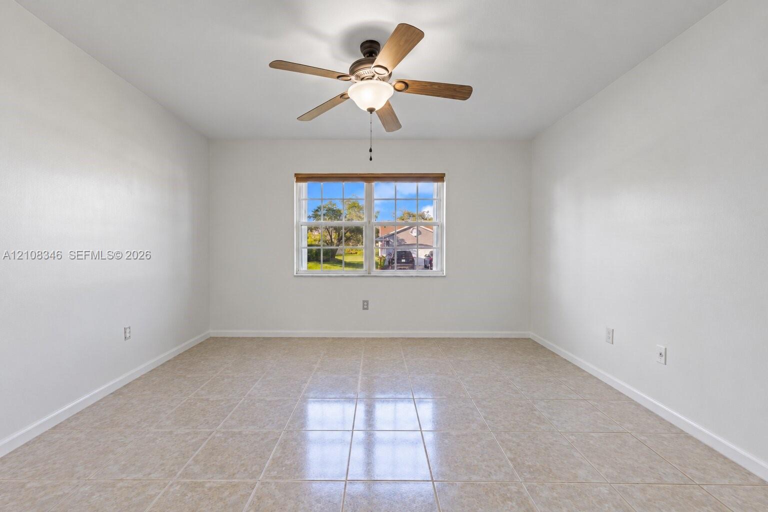 Room featuring ceramic tile flooring, a multi-pane window with a light-filtering shade, and a central ceiling fan with integrated lighting