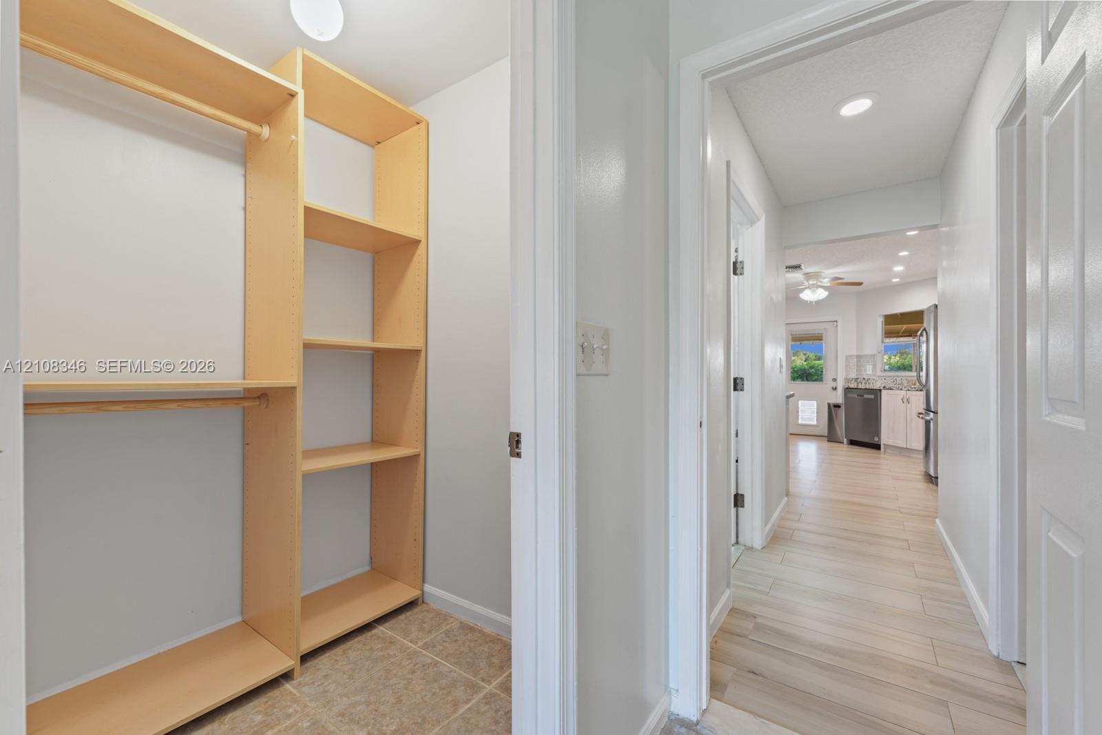 Built-in light-finish wood shelving, integrated hanging rods, recessed ceiling lighting, and wood-finish tile flooring