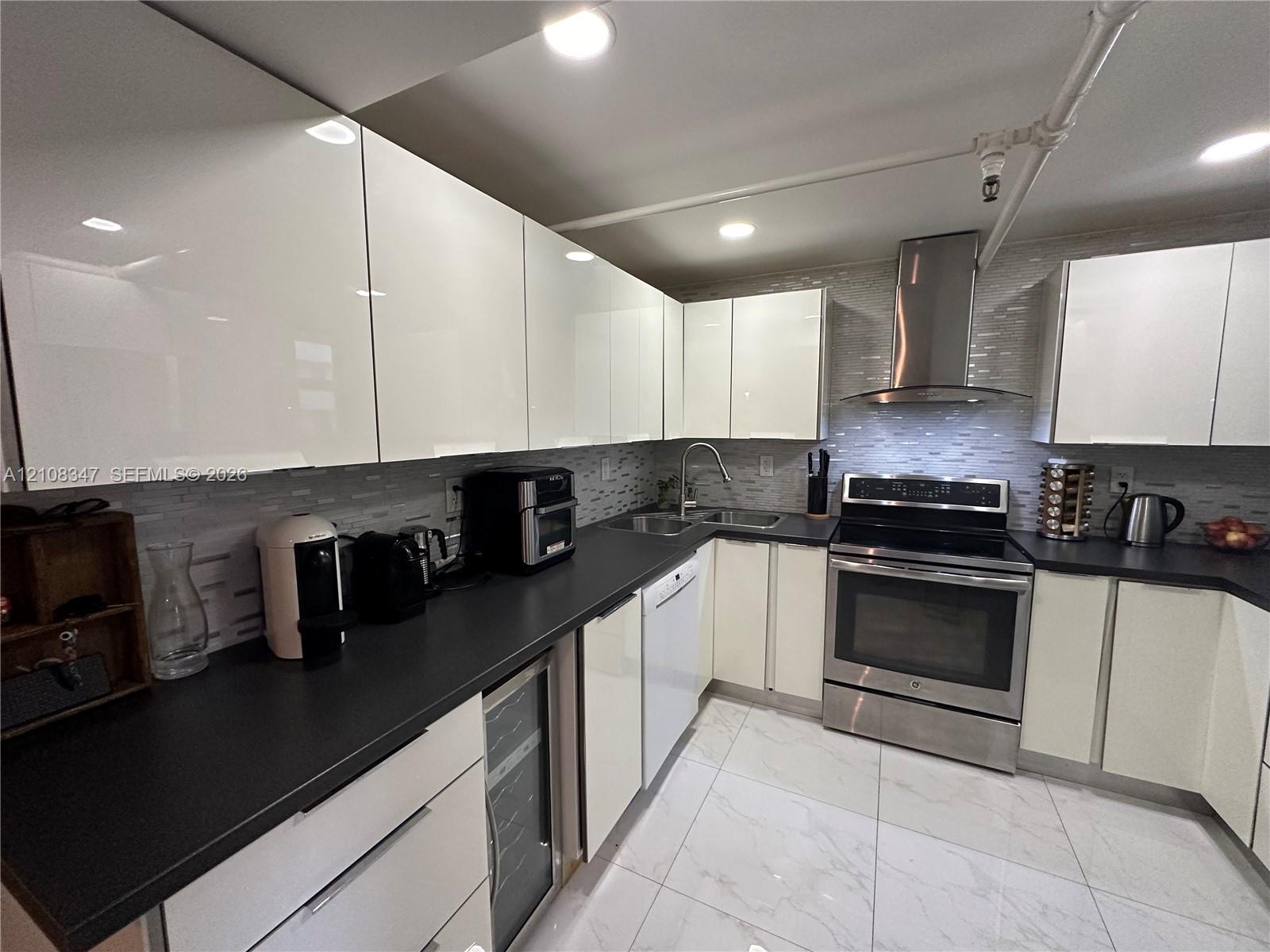 stainless steel chimney-style range hood, integrated wine refrigerator, and stone-finish tile flooring