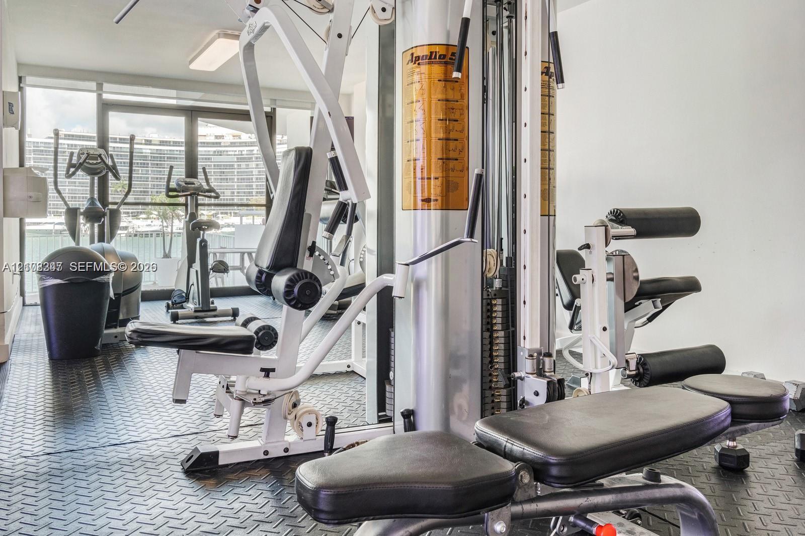 Fitness center featuring black diamond-plate rubber flooring and floor-to-ceiling glass sliding doors