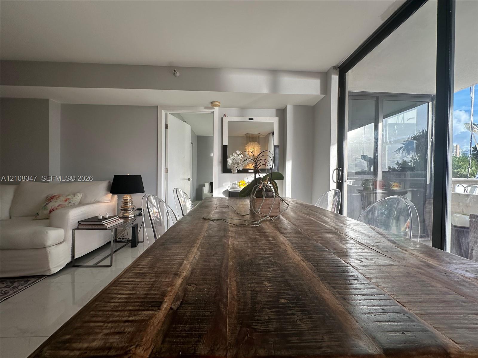 Neutral interior featuring polished tile flooring, full-height glass sliding doors, and a wall-mounted mirror with a black frame