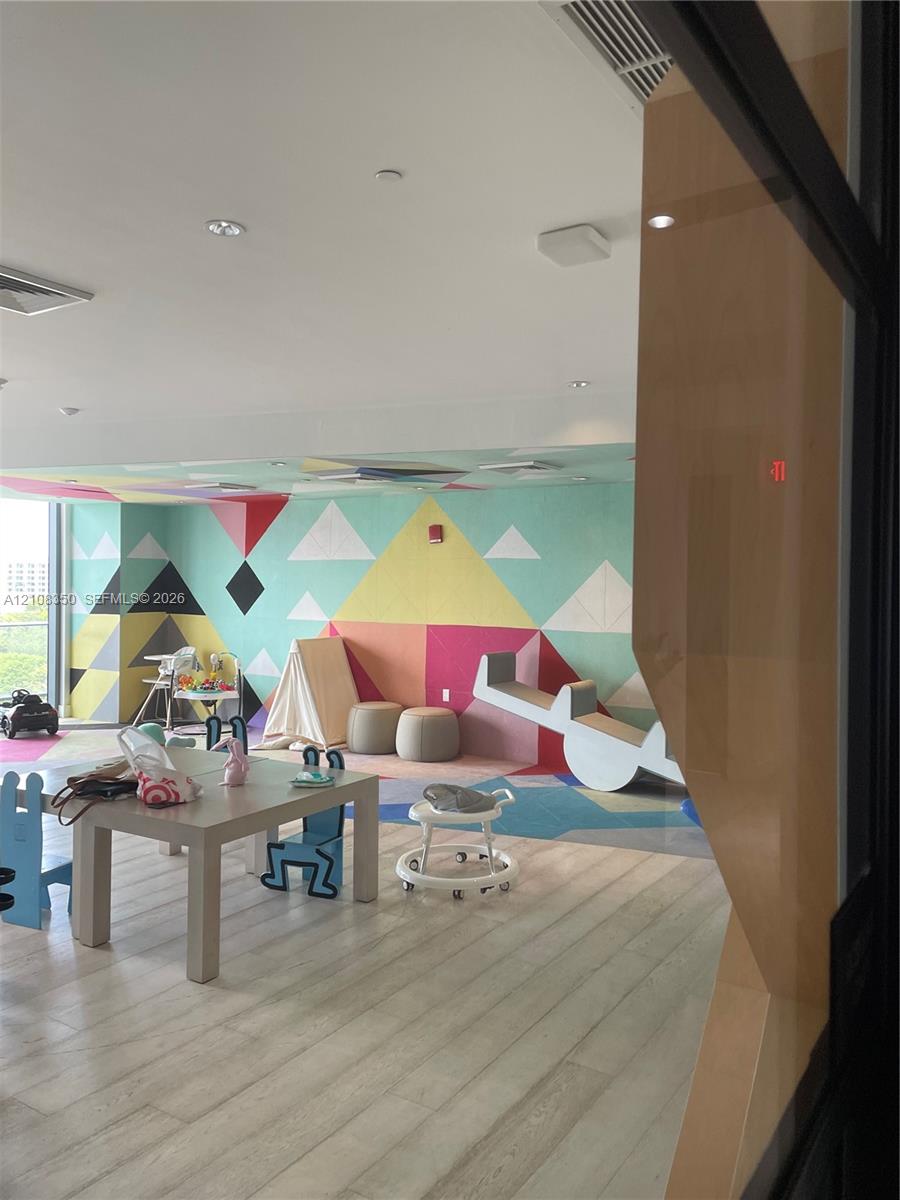 Common area featuring wood-finish flooring, recessed ceiling lighting, and geometric mural wall covering
