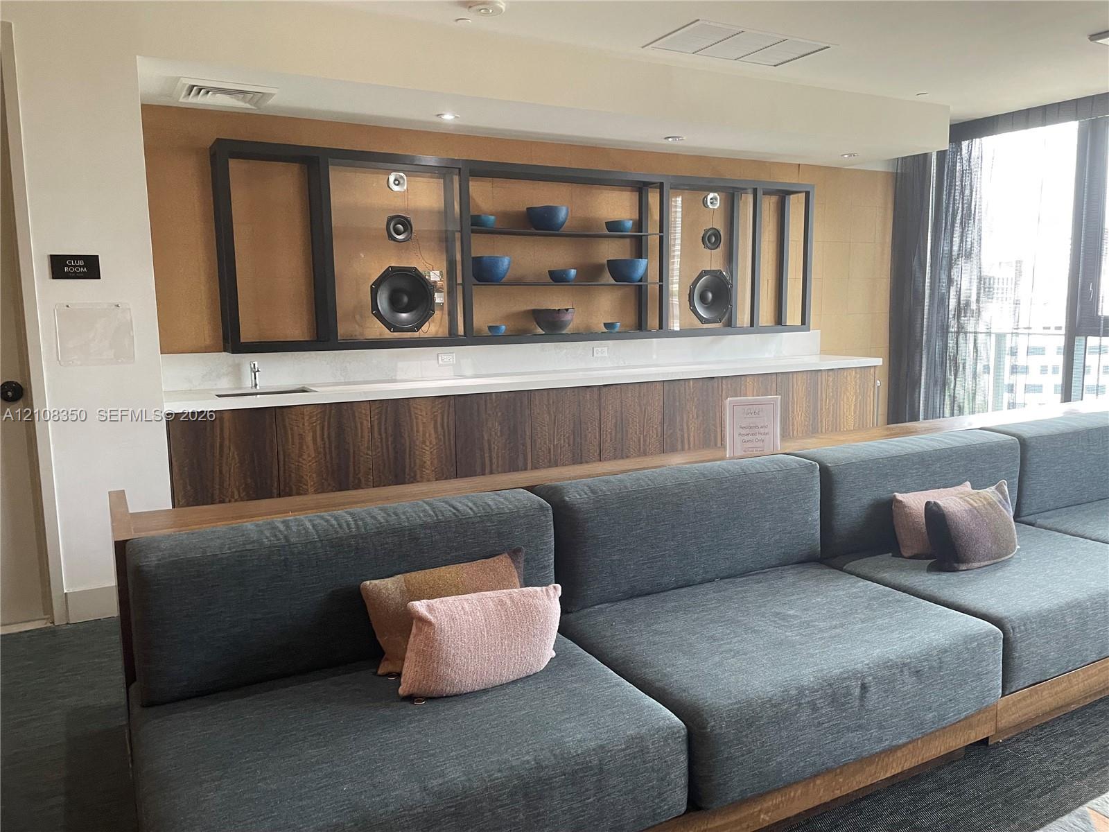 Custom built-in cabinetry with wood-finish lower panels, recessed shelving, integrated speakers, and a solid-surface countertop