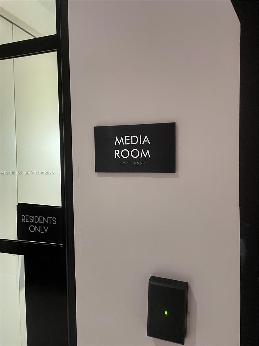 Media room featuring black signage, electronic key fob access control, and glass-paneled entry door