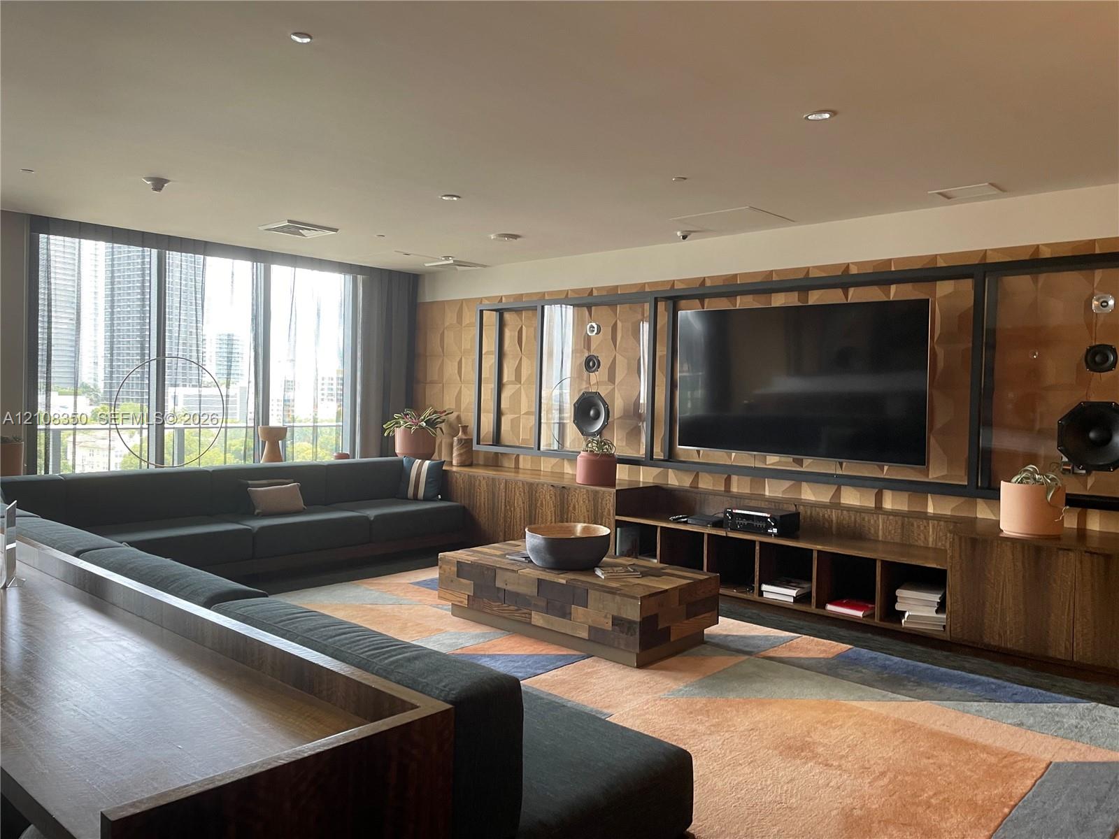 Floor-to-ceiling windows, custom built-in wood cabinetry with integrated shelving, geometric textured wall paneling, and recessed lighting