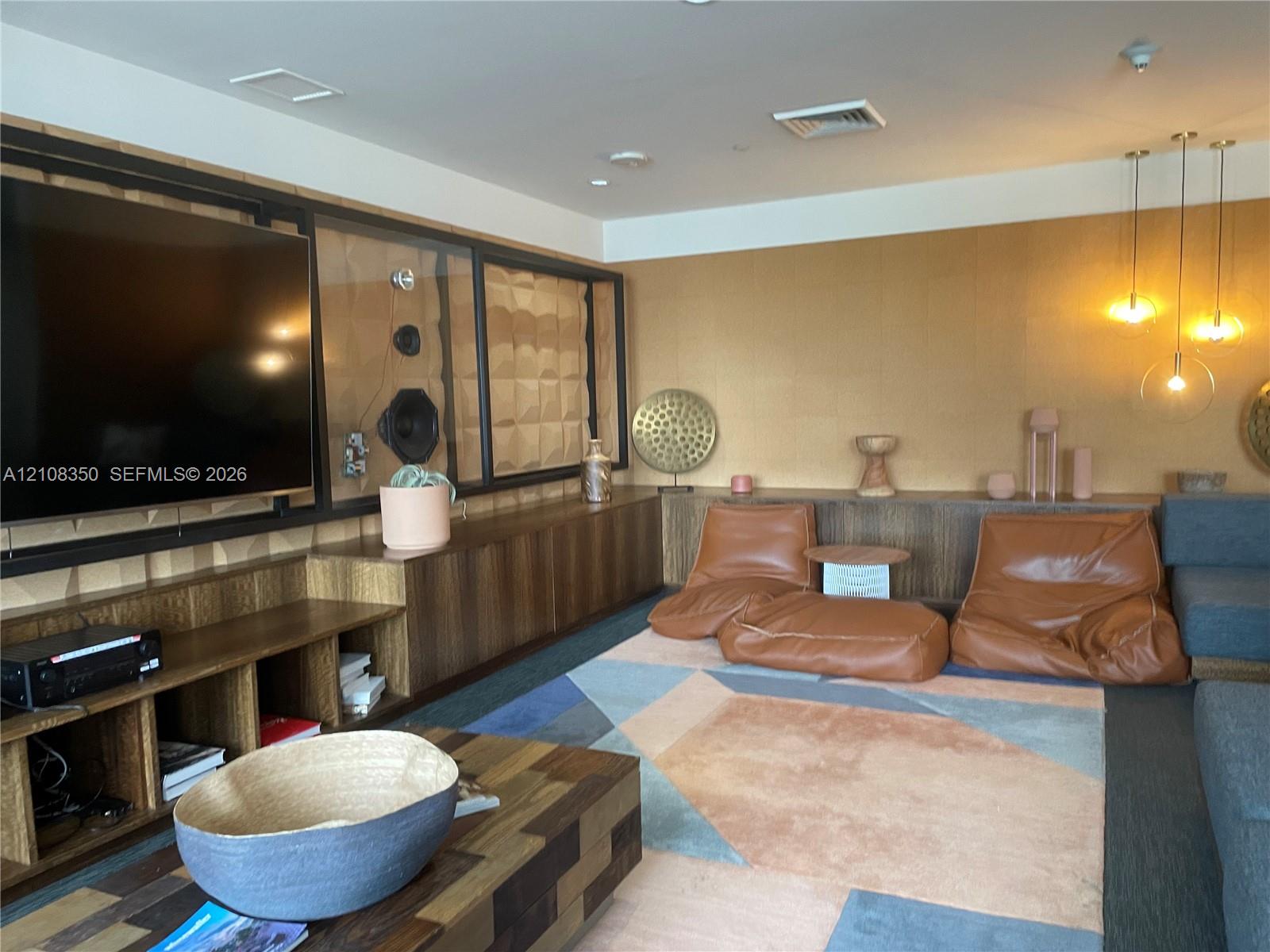 Custom built-in wood cabinetry, three-pendant modern lighting, integrated media wall with geometric wall panels, and warm-toned textured wall finish