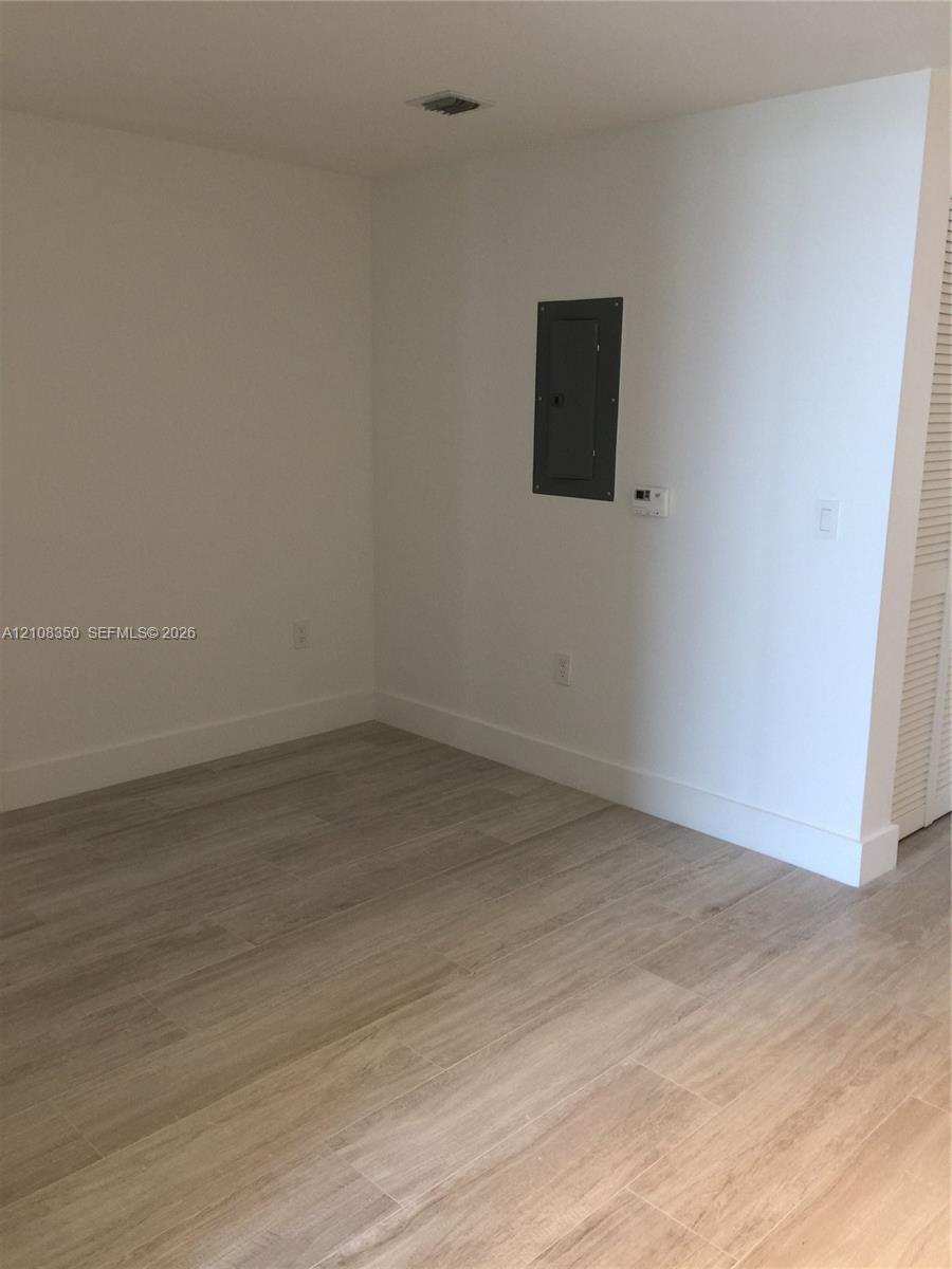 Neutral interior space featuring wood-finish flooring and louvered closet doors