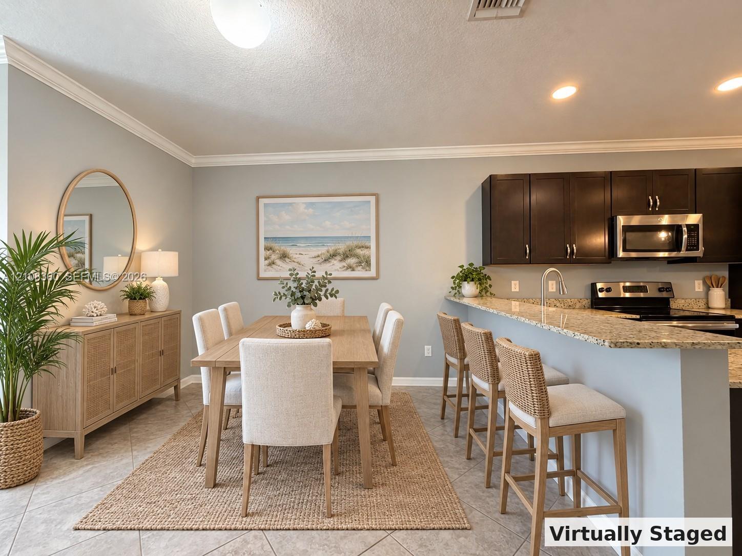 Kitchen featuring dark cabinetry, stone-surface breakfast bar, and stainless steel appliances, complemented by tile flooring and crown molding Kitchen featuring dark cabinetry, stone-surface breakfast bar, and stainless steel appliances, complemented by tile flooring and crown molding