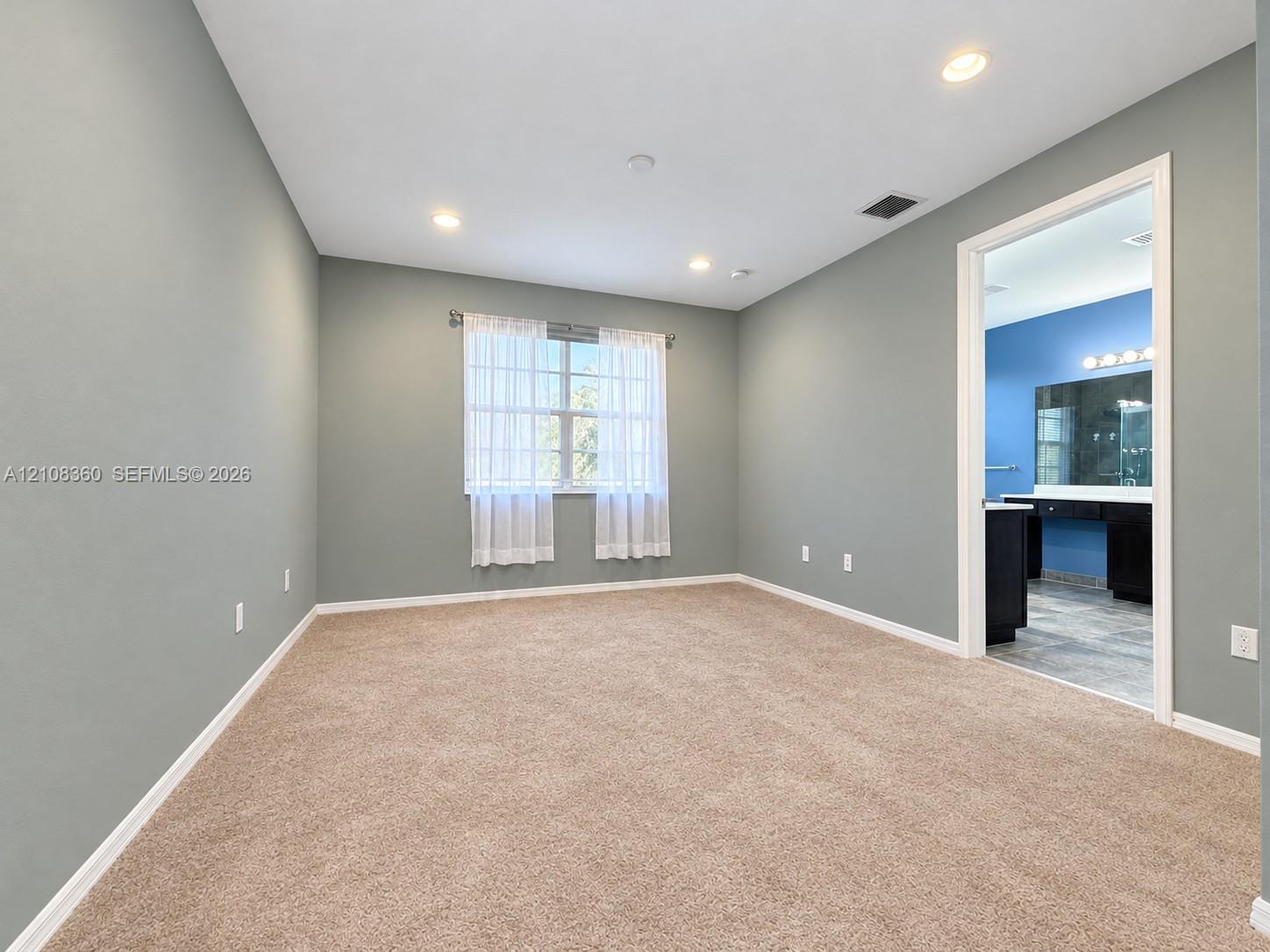Spacious interior featuring neutral-toned carpeting, recessed lighting, and a window with exterior exposure