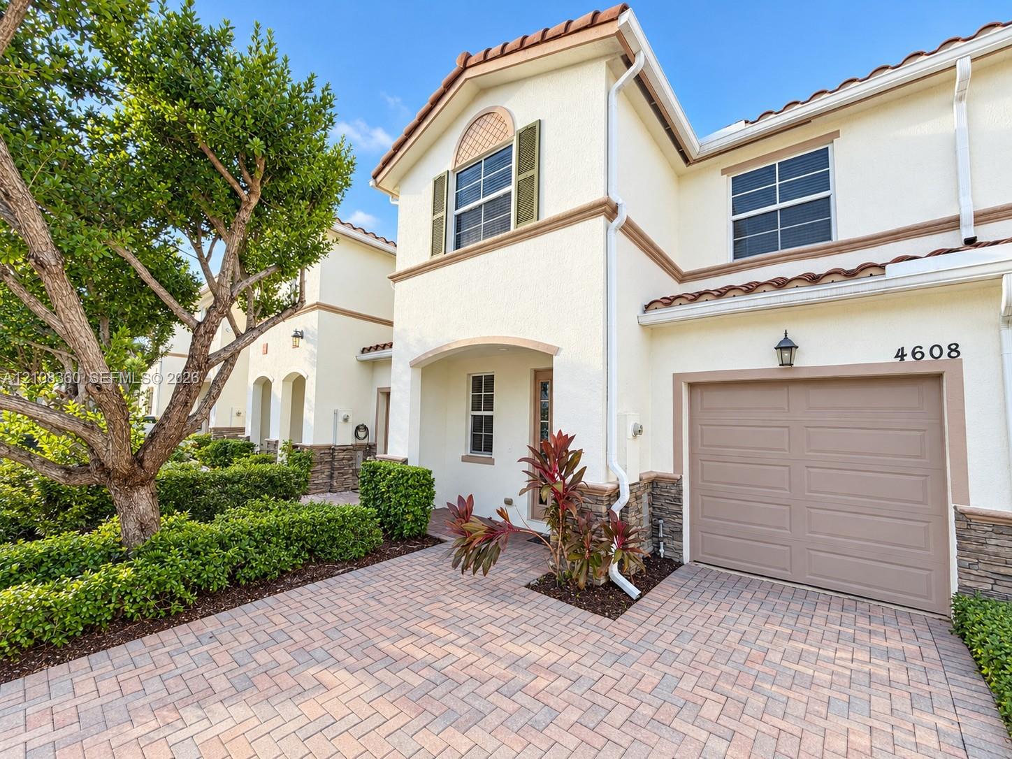Stucco exterior featuring decorative stone veneer accents, arched entryway, paved driveway, and tile roofline Stucco exterior featuring decorative stone veneer accents, arched entryway, paved driveway, and tile roofline