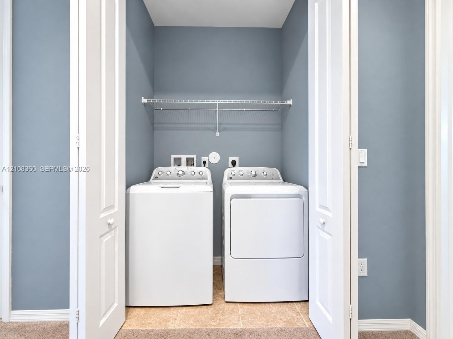 Laundry closet featuring bifold doors, tile flooring, and integrated wire shelving