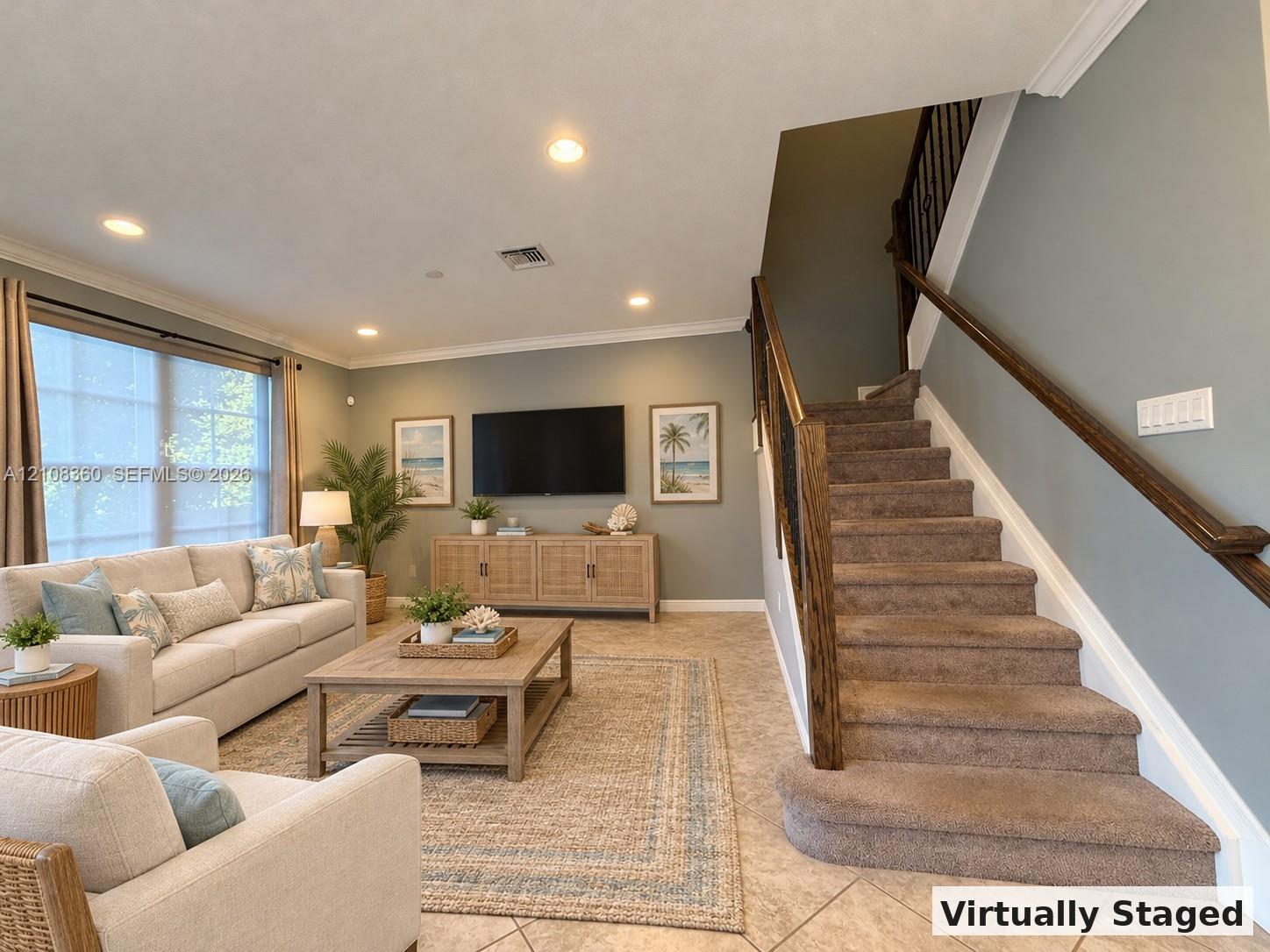 Open-concept interior featuring large-format tile flooring, recessed lighting, crown molding, and a staircase with stained wood handrails and metal balusters Open-concept interior featuring large-format tile flooring, recessed lighting, crown molding, and a staircase with stained wood handrails and metal balusters