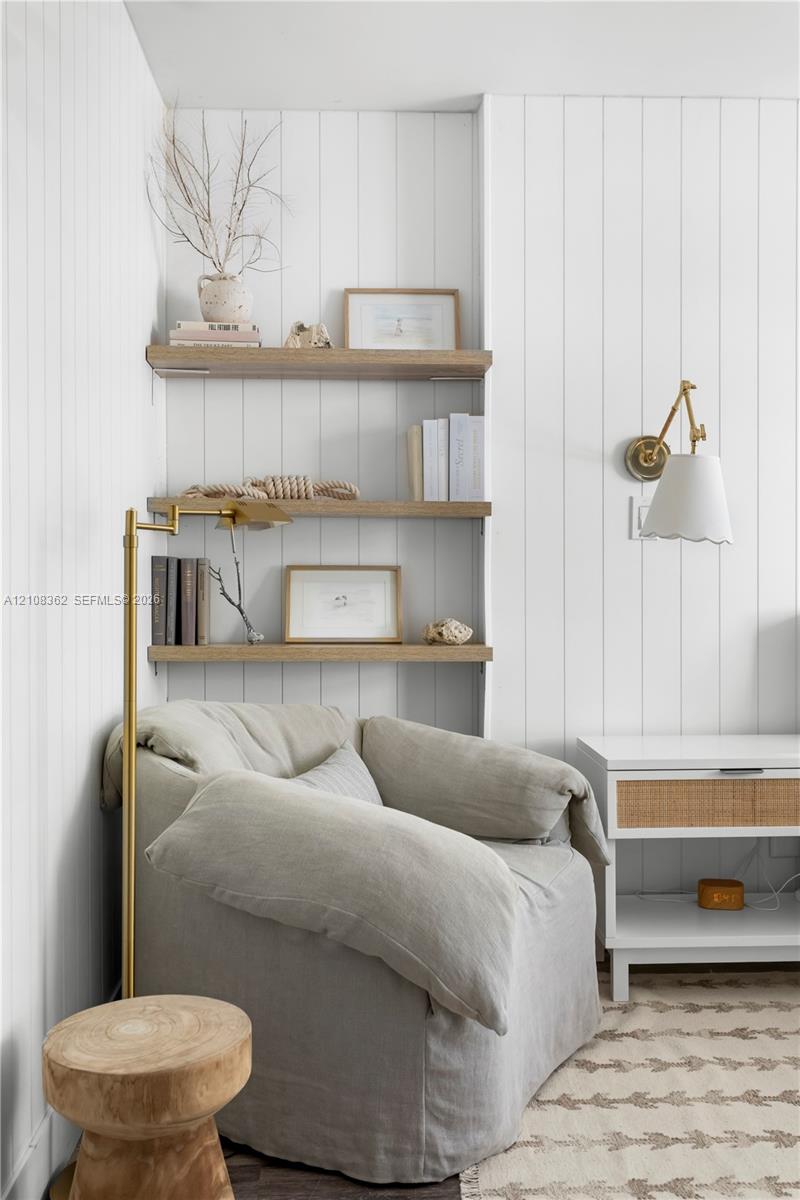 Vertical wood-paneled walls, built-in light-tone wood shelving, and brass swing-arm wall sconce