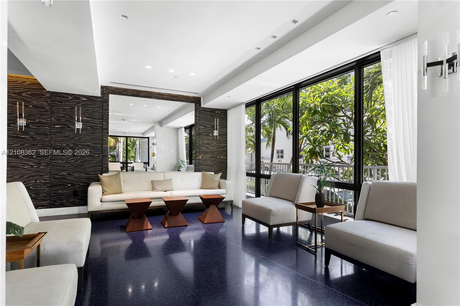 Interior space featuring floor-to-ceiling windows, dark high-gloss flooring, recessed lighting, wall-mounted light fixtures, and dark-toned textured wall paneling