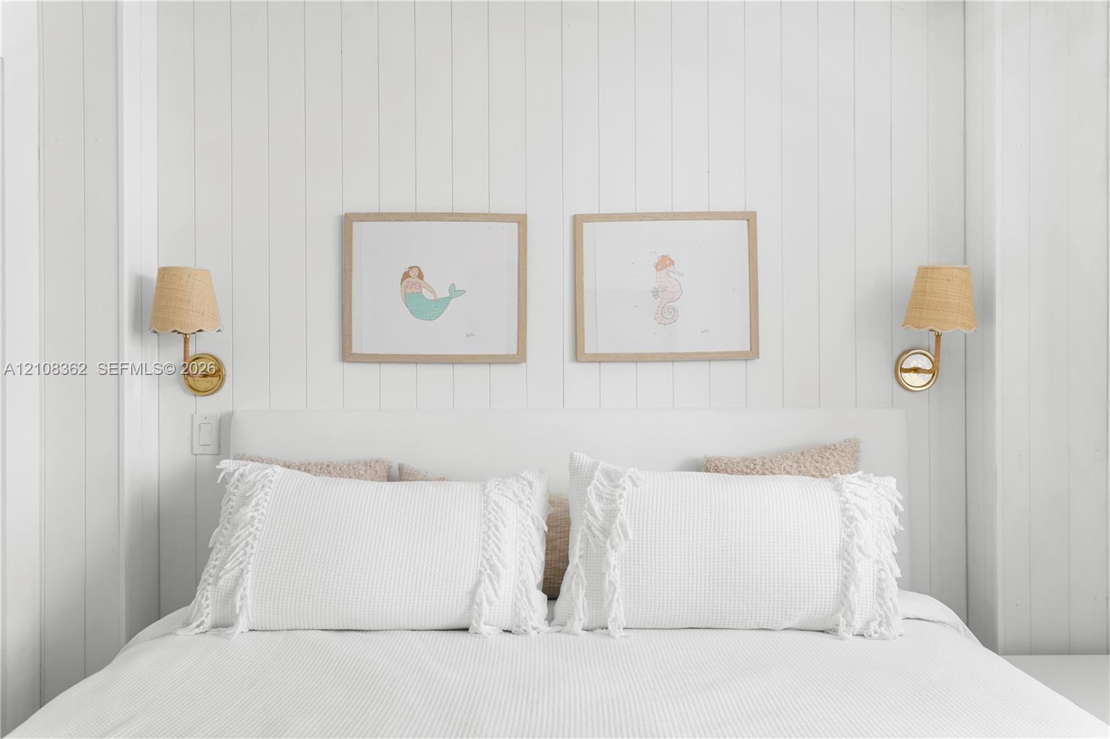 Vertical plank wood wall paneling with dual brass-finish wall-mounted sconces featuring textured shades