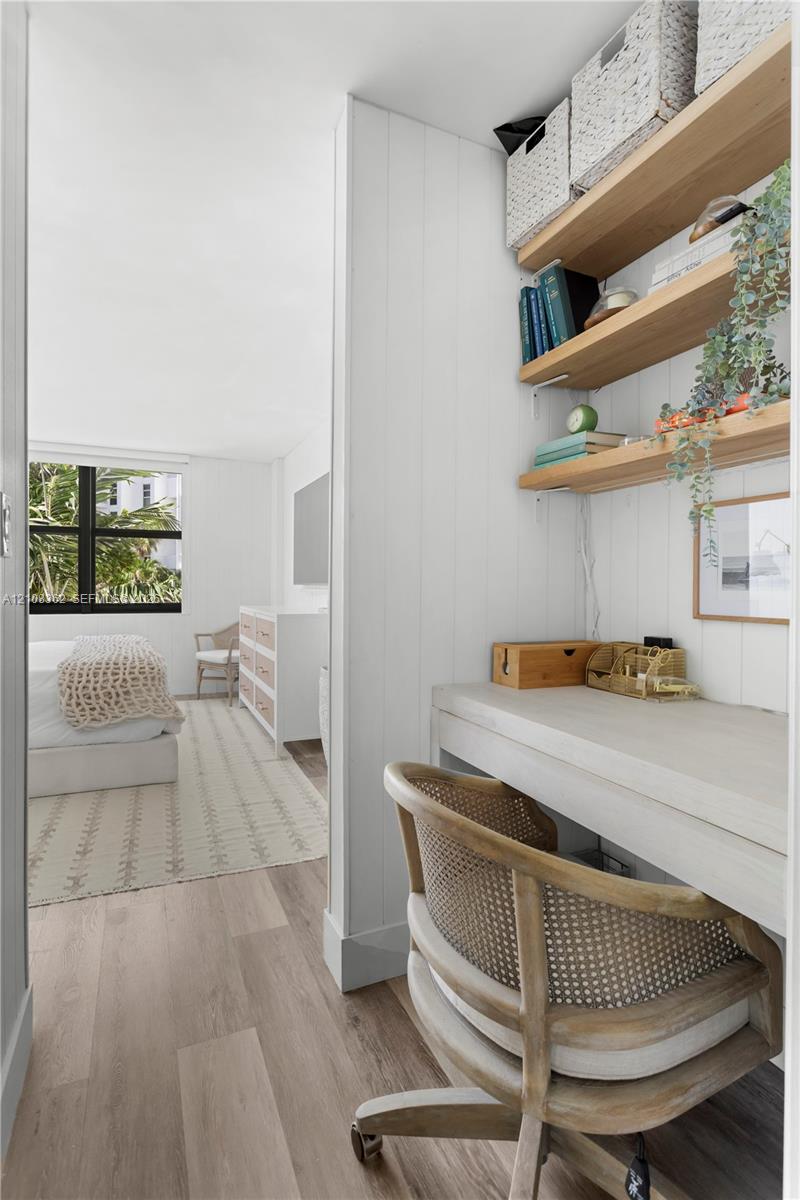 Built-in desk area with wood-finish flooring, vertical panel wall detailing, and open wood shelving