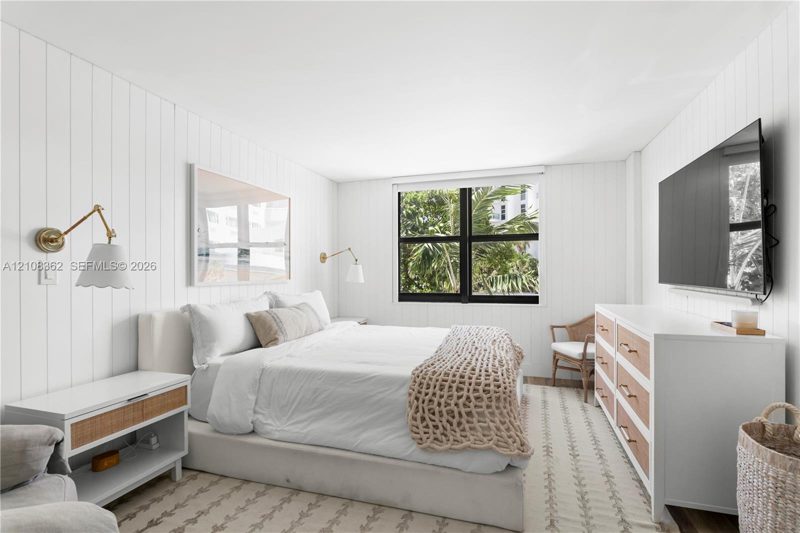 Vertical shiplap wall paneling, dual gold-finish articulating wall sconces, and a multi-pane window featuring exterior greenery