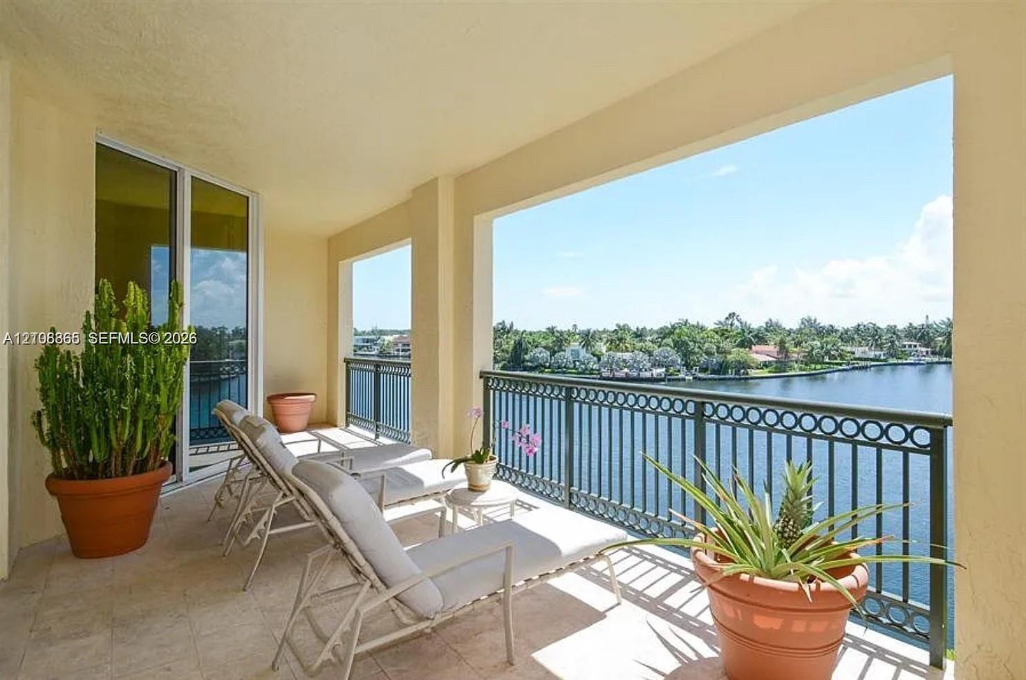 Covered balcony featuring stone-finish tile flooring and ornate metal railings