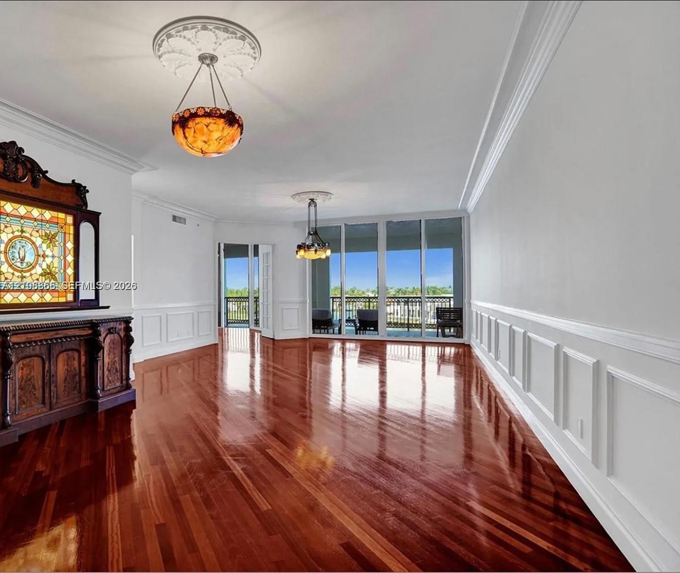Polished wood-finish flooring, decorative ceiling medallions, custom wainscoting, built-in stained-glass cabinetry, and floor-to-ceiling sliding glass doors