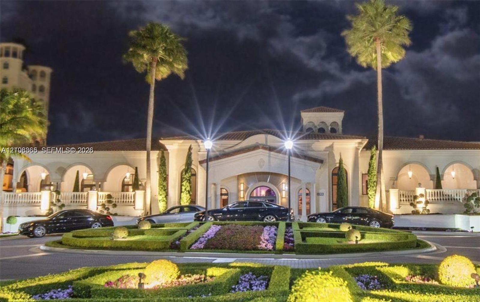 Mediterranean-style exterior featuring a covered portico, arched loggias, terracotta roof tiles, and manicured ornamental gardens