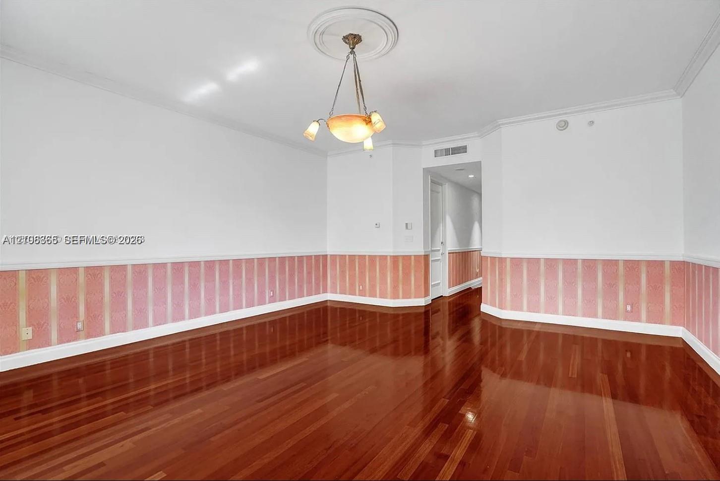 Interior space featuring high-gloss wood-finish flooring, decorative wall wainscoting, and a central ceiling medallion with a multi-arm light fixture