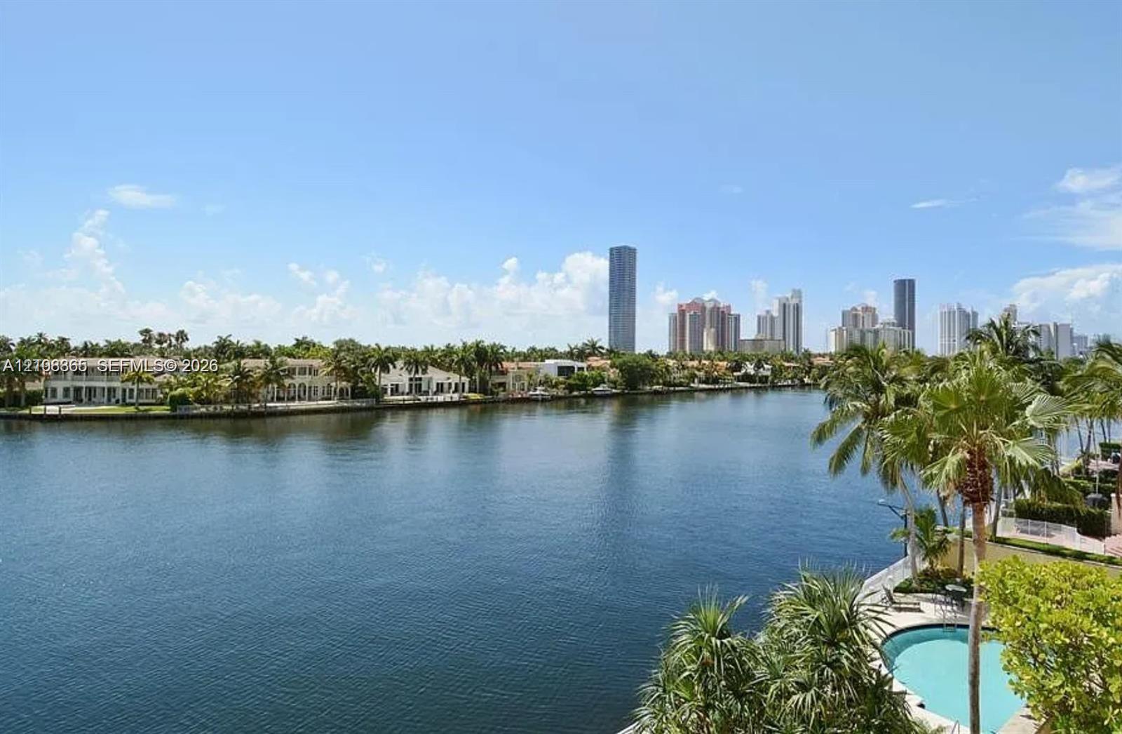 Waterfront property featuring a canal, private swimming pool, mature palm trees, and coastal skyline horizon Waterfront property featuring a canal, private swimming pool, mature palm trees, and coastal skyline horizon