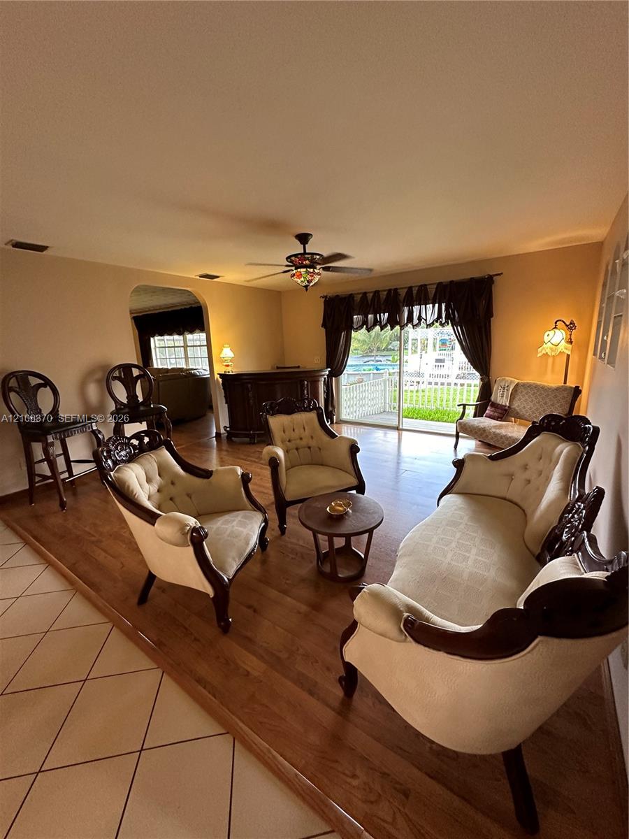 Raised wood-finish flooring, tile flooring, arched wall opening, and sliding glass doors