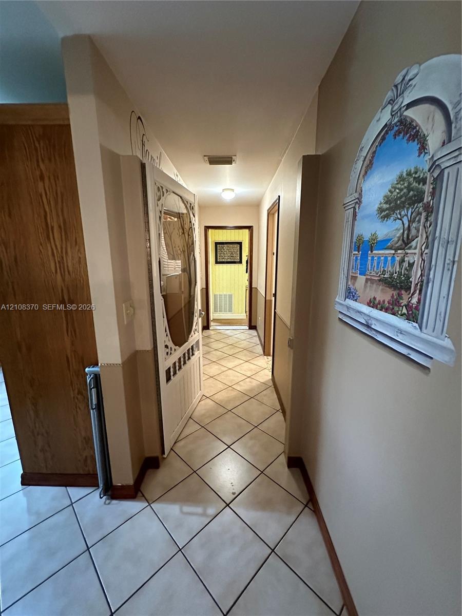Ceramic tile flooring laid in a diagonal pattern, wood-finish interior doors, and neutral wall tones with decorative wall molding