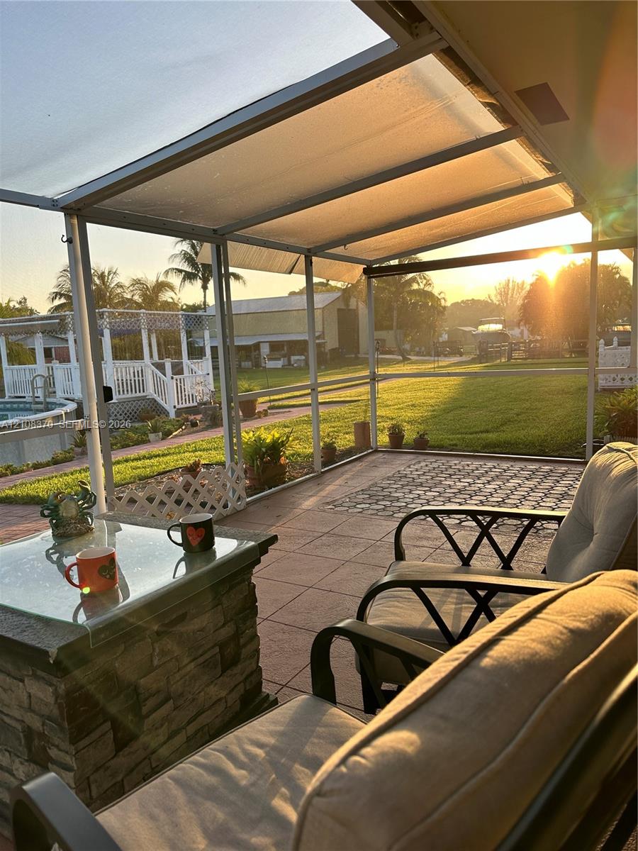 Screen-enclosed patio featuring a paver floor, stone-finish base, and metal framing