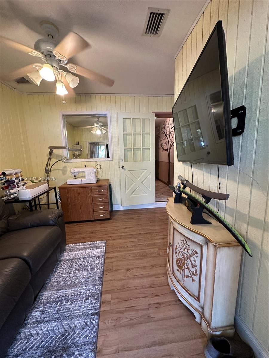 Interior space featuring wood-finish flooring, vertical panel wall detailing, and a multi-pane door with a cross-buck design