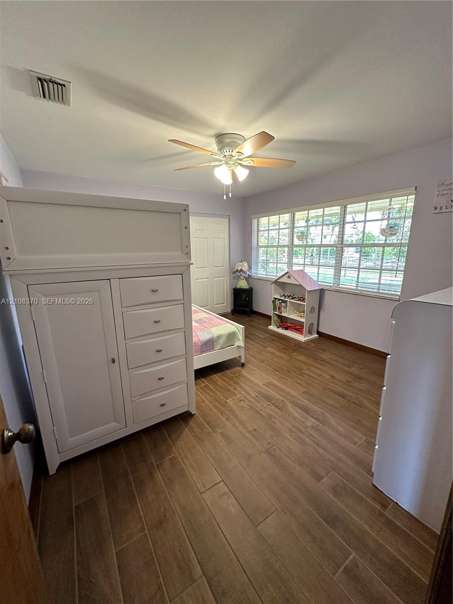 Wood-finish flooring, multi-pane window with grid pattern, and ceiling fan with integrated lighting
