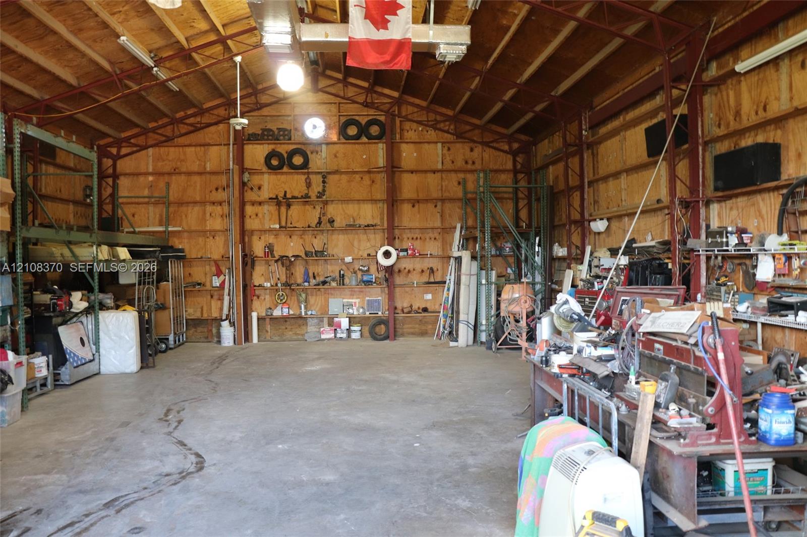 Expansive interior workshop featuring exposed structural steel framing, high vaulted ceilings with integrated lighting, concrete flooring, and plywood wall paneling