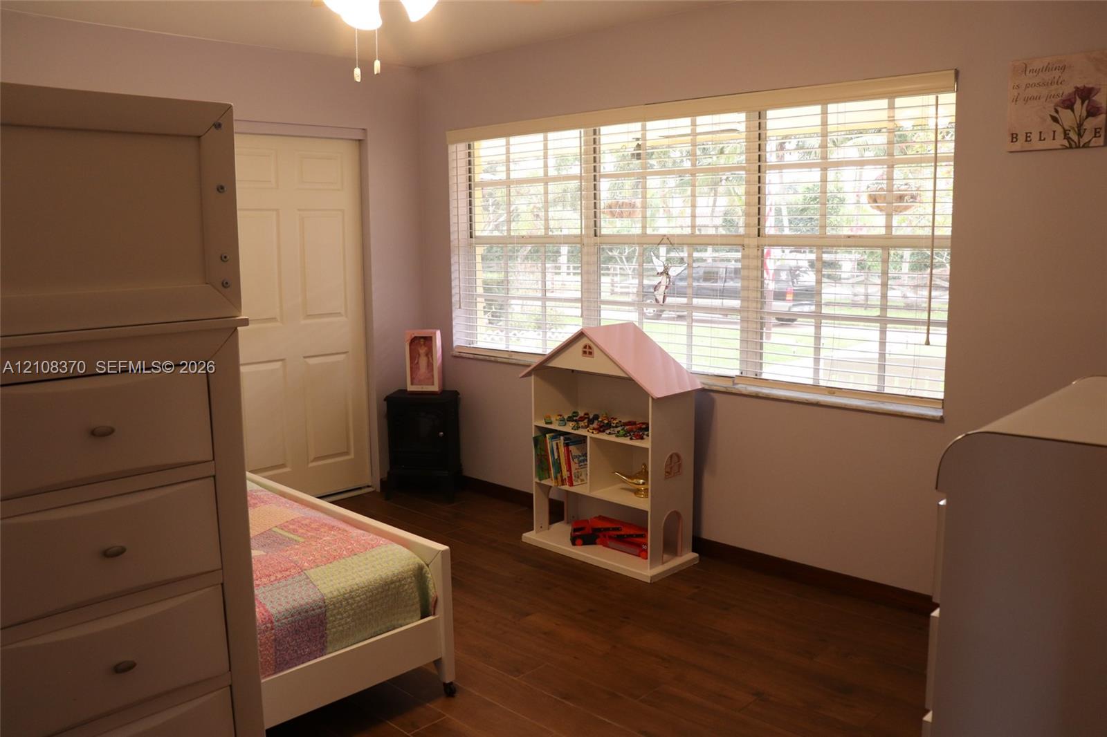 Wood-finish flooring, multi-pane window with integrated blinds, and ceiling fan with integrated lighting fixture