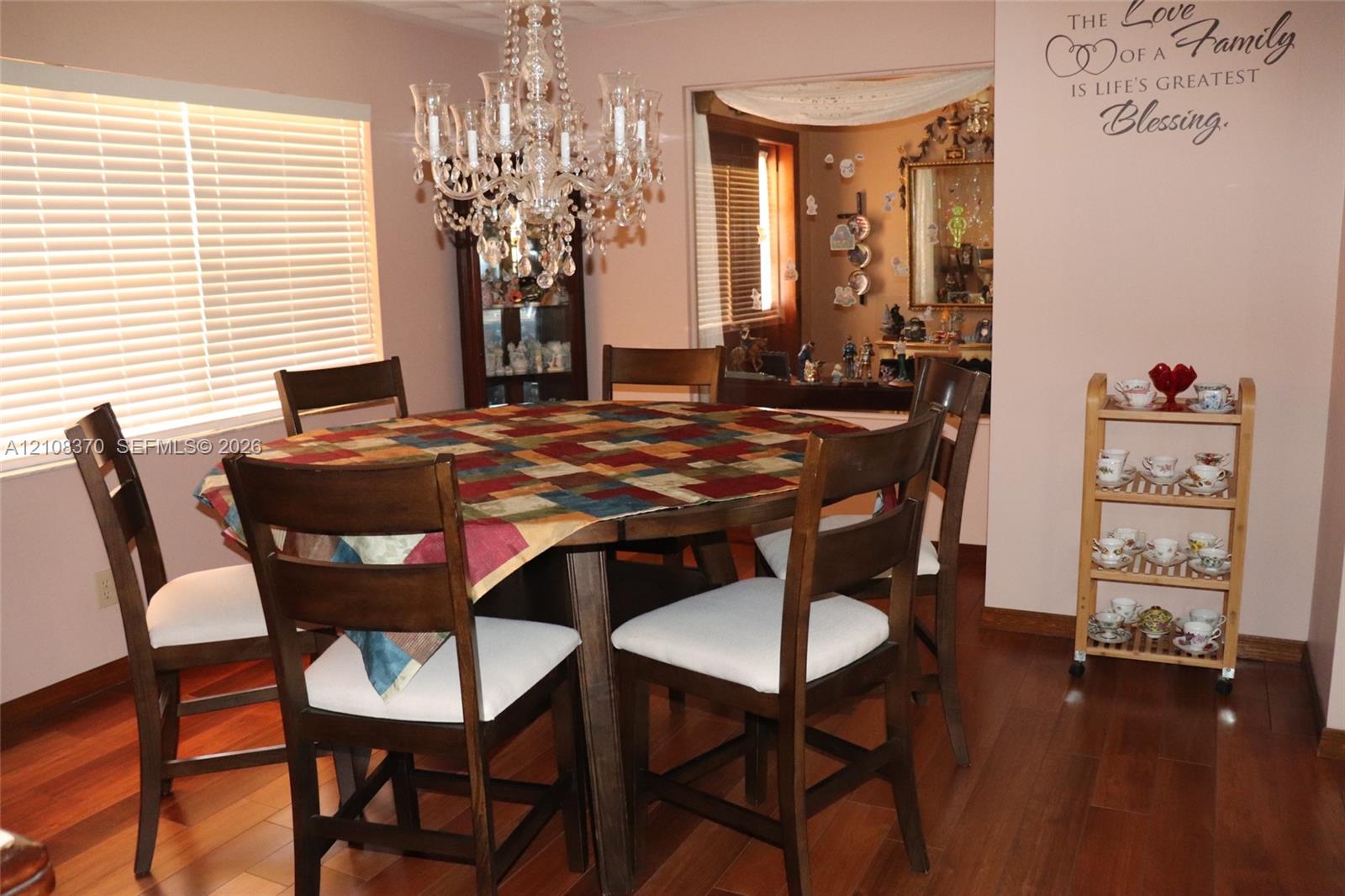 Dining area featuring wood-finish flooring, a multi-tiered crystal chandelier, and windows with horizontal blinds