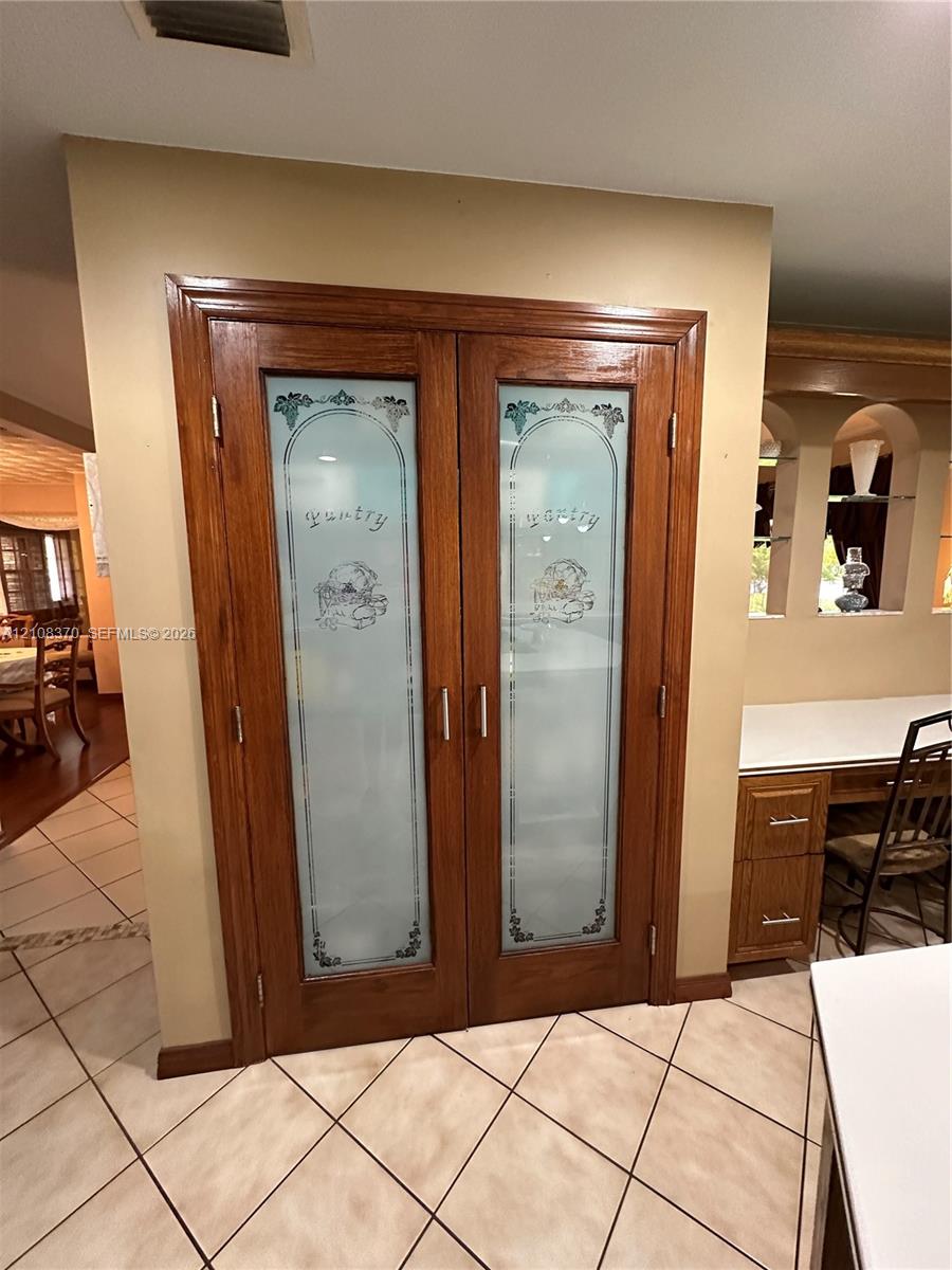 Double pantry doors featuring wood framing and decorative etched glass inserts with silver-tone hardware