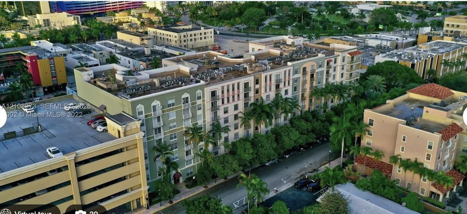 Multi-story building featuring an arched facade, decorative balconies, stucco exterior, and integrated parking structure