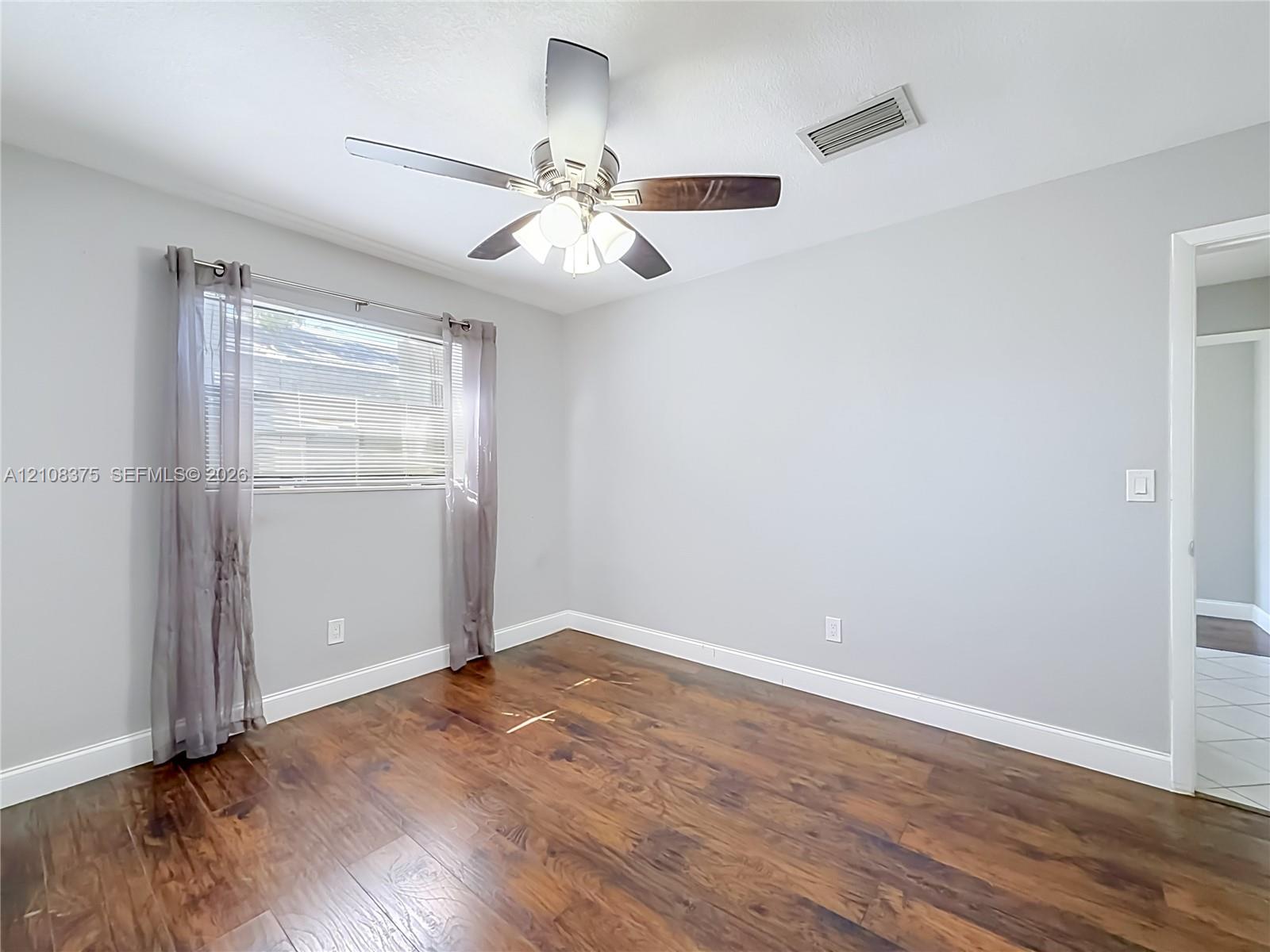 Wood-finish flooring, neutral wall tones, and a ceiling fan with integrated lighting