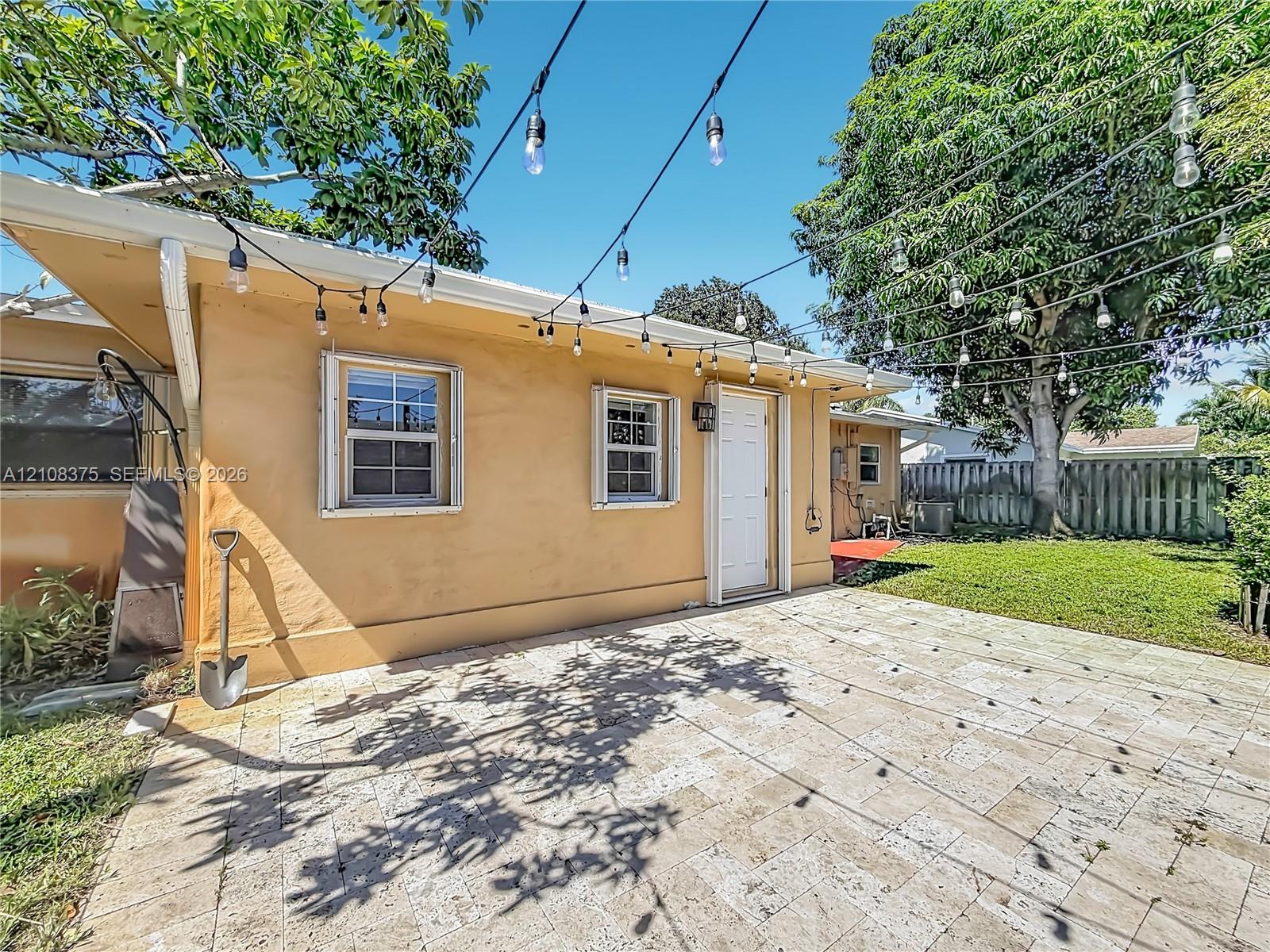 Exterior patio featuring stone paver flooring, string lighting, and direct access to the backyard