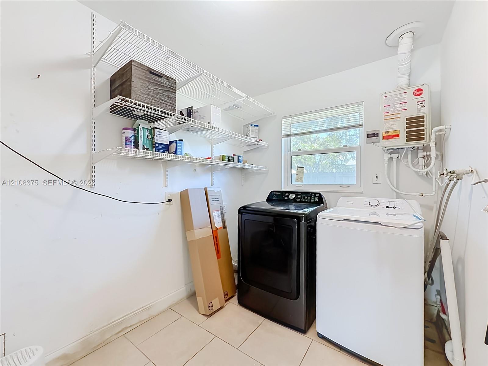 Laundry area featuring tile flooring, multi-tiered wire shelving, a window with horizontal blinds, and an integrated tankless water heater