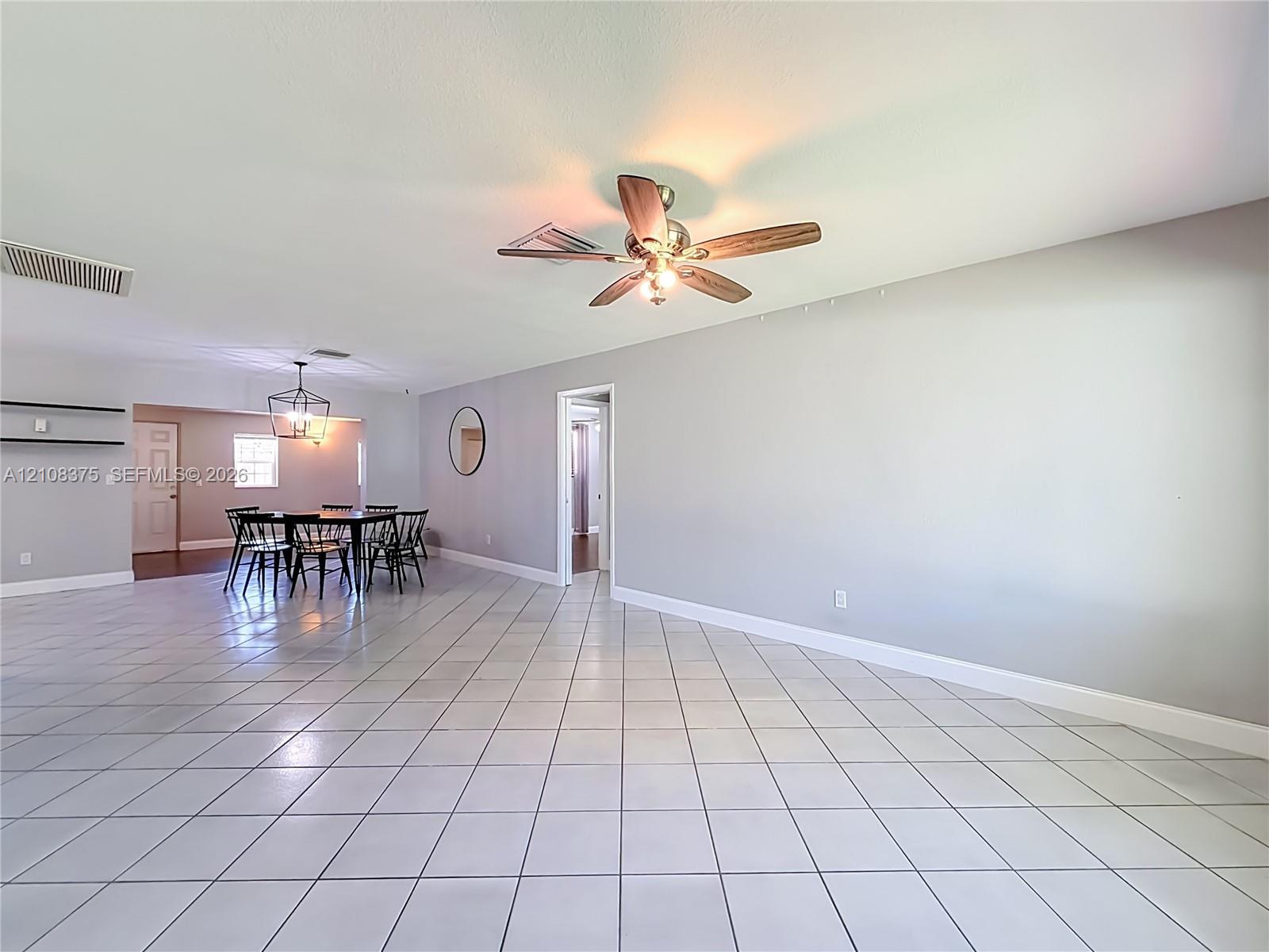 Large living area featuring neutral-toned tile flooring, recessed lighting, and a ceiling fan with integrated lighting