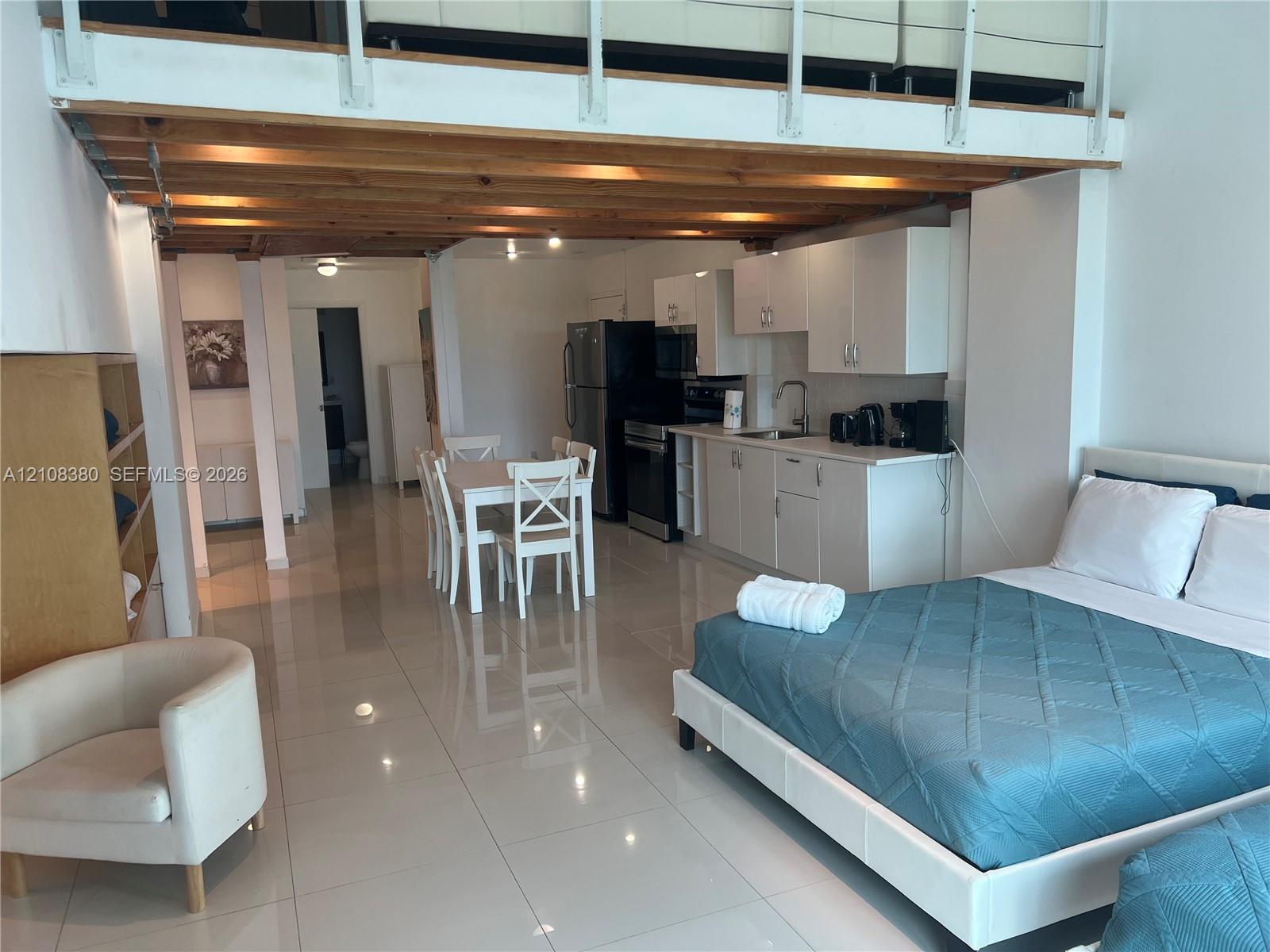 High-ceiling interior featuring an exposed wood-beam loft structure, polished tile flooring, white cabinetry, and recessed lighting High-ceiling interior featuring an exposed wood-beam loft structure, polished tile flooring, white cabinetry, and recessed lighting