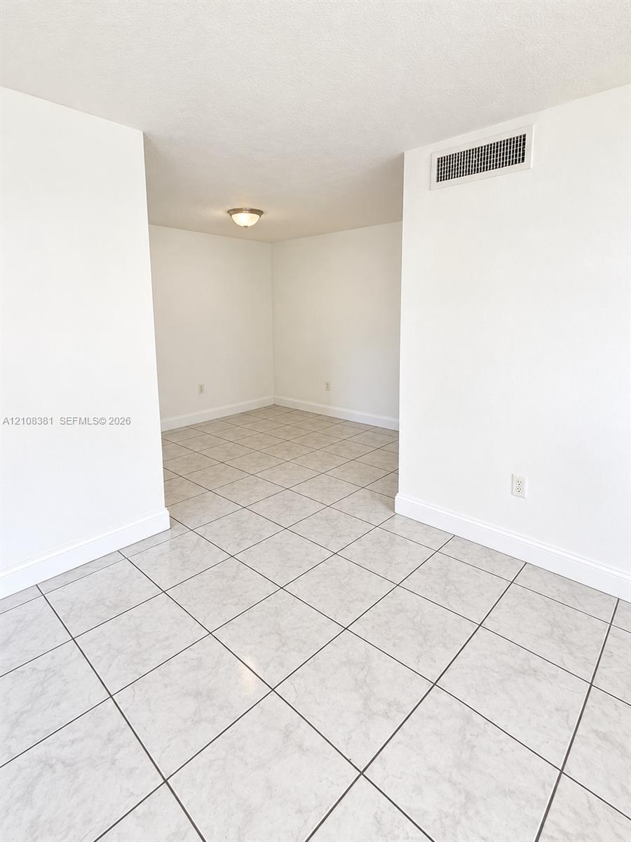 Neutral-toned ceramic tile flooring, crisp white walls, and a center-mounted flush mount light fixture