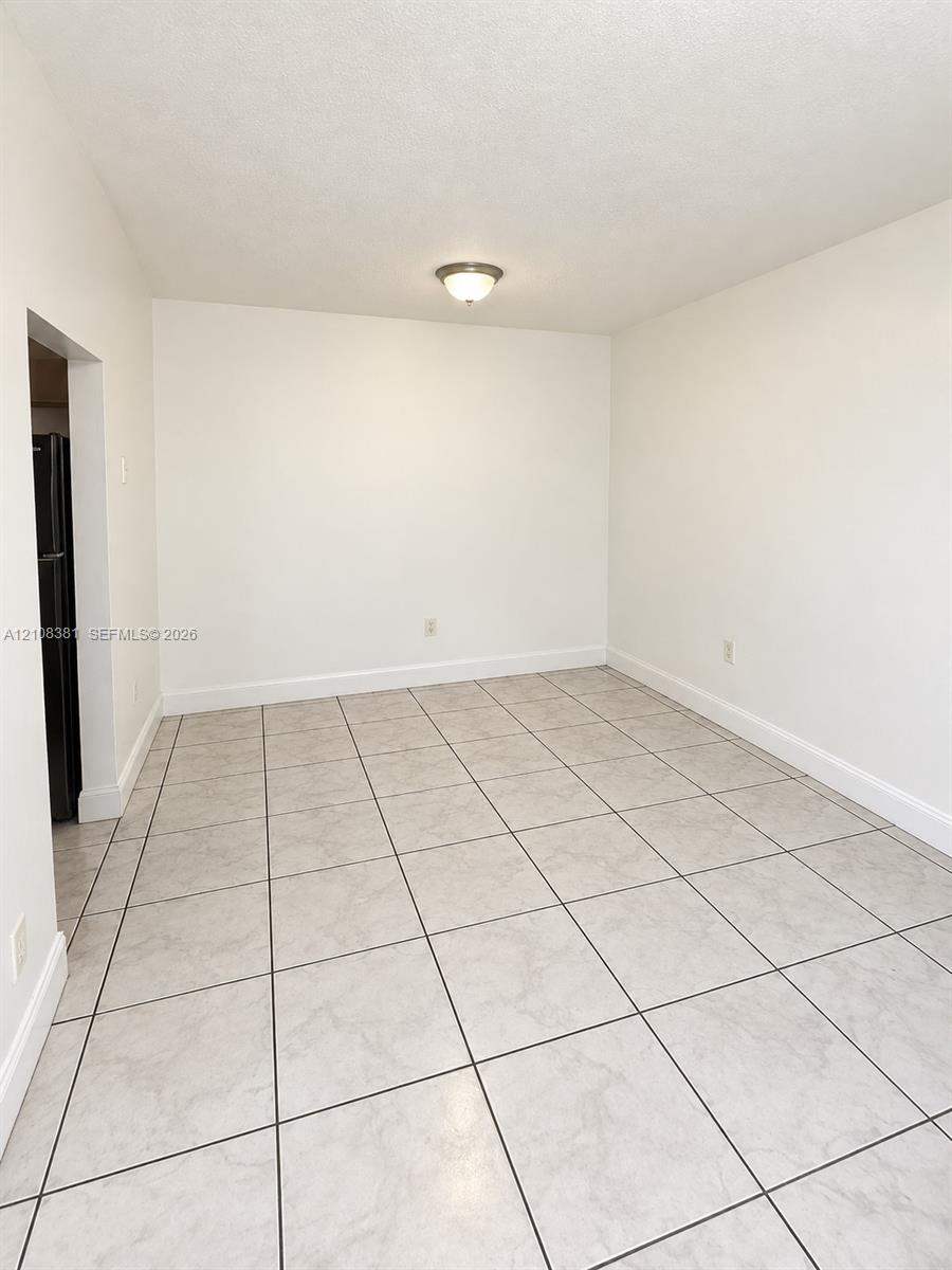 Neutral-toned ceramic tile flooring, smooth white wall finishes, and glass sliding door access to exterior space