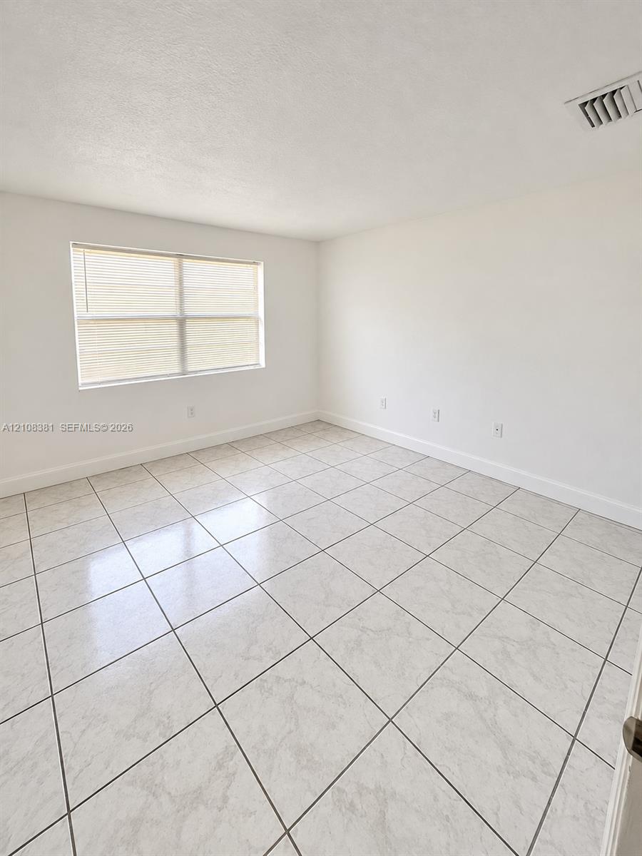 Interior space featuring neutral white walls and square stone-finish tile flooring