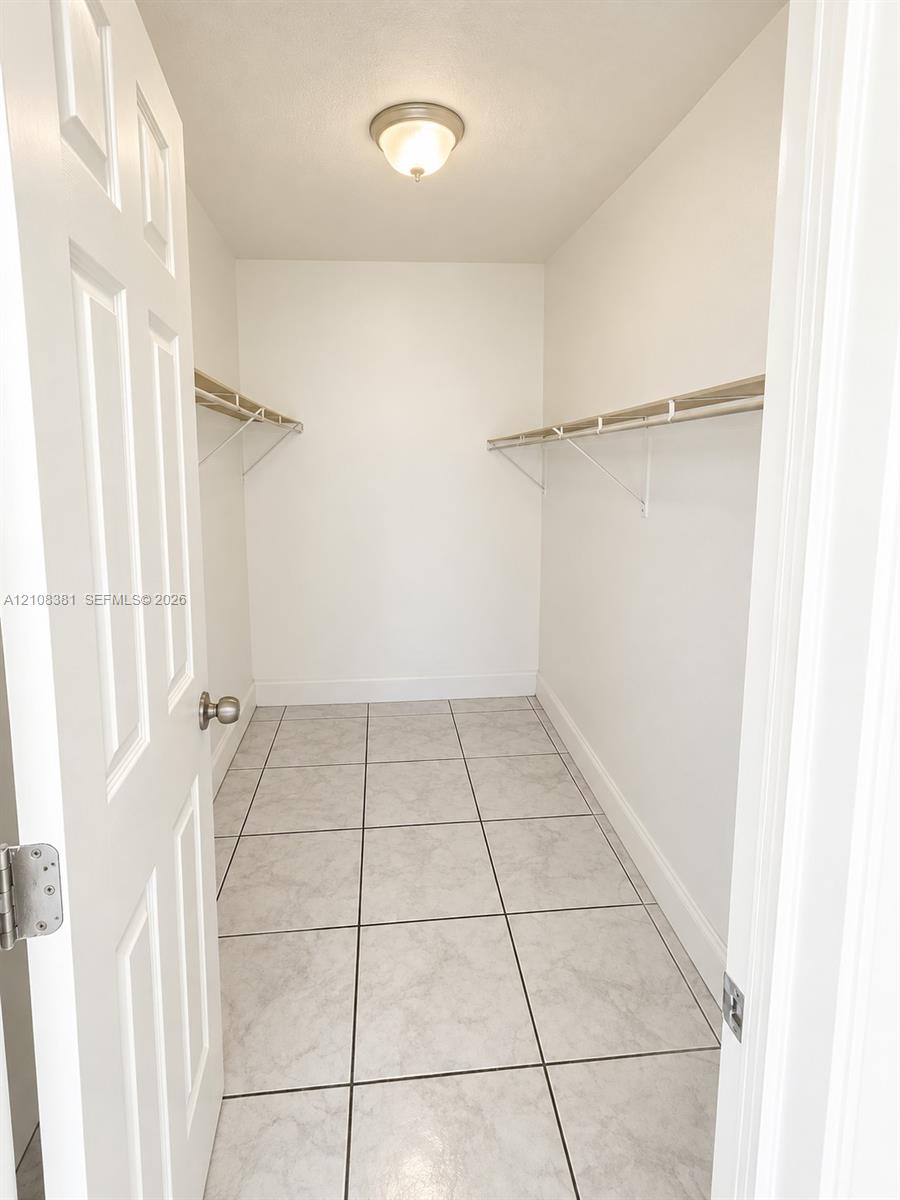 Neutral interior space featuring stone-finish tile flooring, white wall finishes, and a single window with blinds