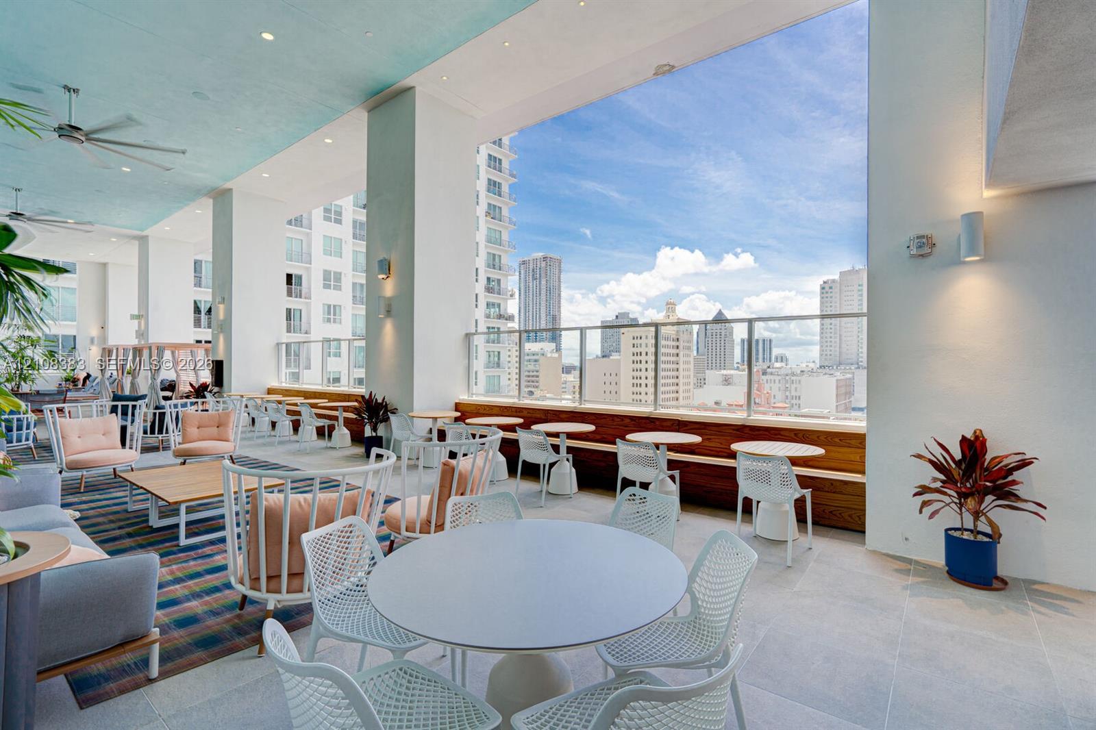 Covered rooftop terrace featuring large-format stone-finish tile flooring, recessed ceiling lighting, built-in wooden bench seating, and glass panel railings