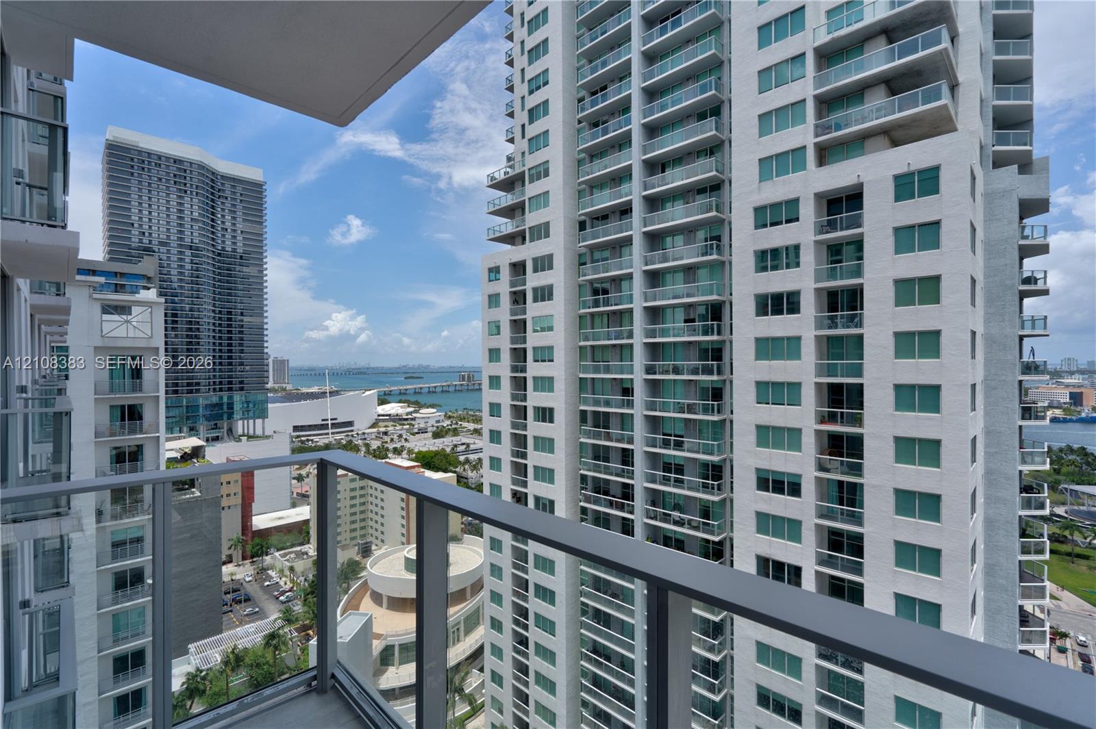 Private balcony featuring a metal and glass railing, concrete flooring, and an expansive urban horizon