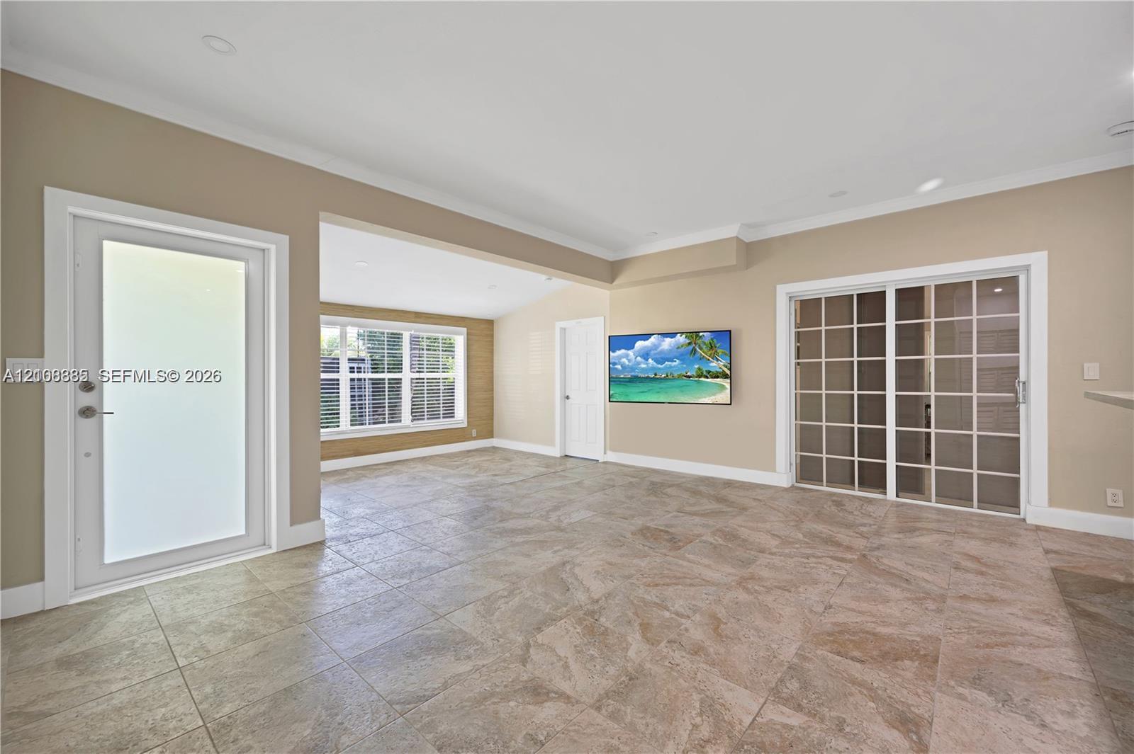 Open-concept interior featuring large-format tile flooring, multi-pane glass sliding doors, recessed ceiling lighting, and a frosted glass entry door Open-concept interior featuring large-format tile flooring, multi-pane glass sliding doors, recessed ceiling lighting, and a frosted glass entry door